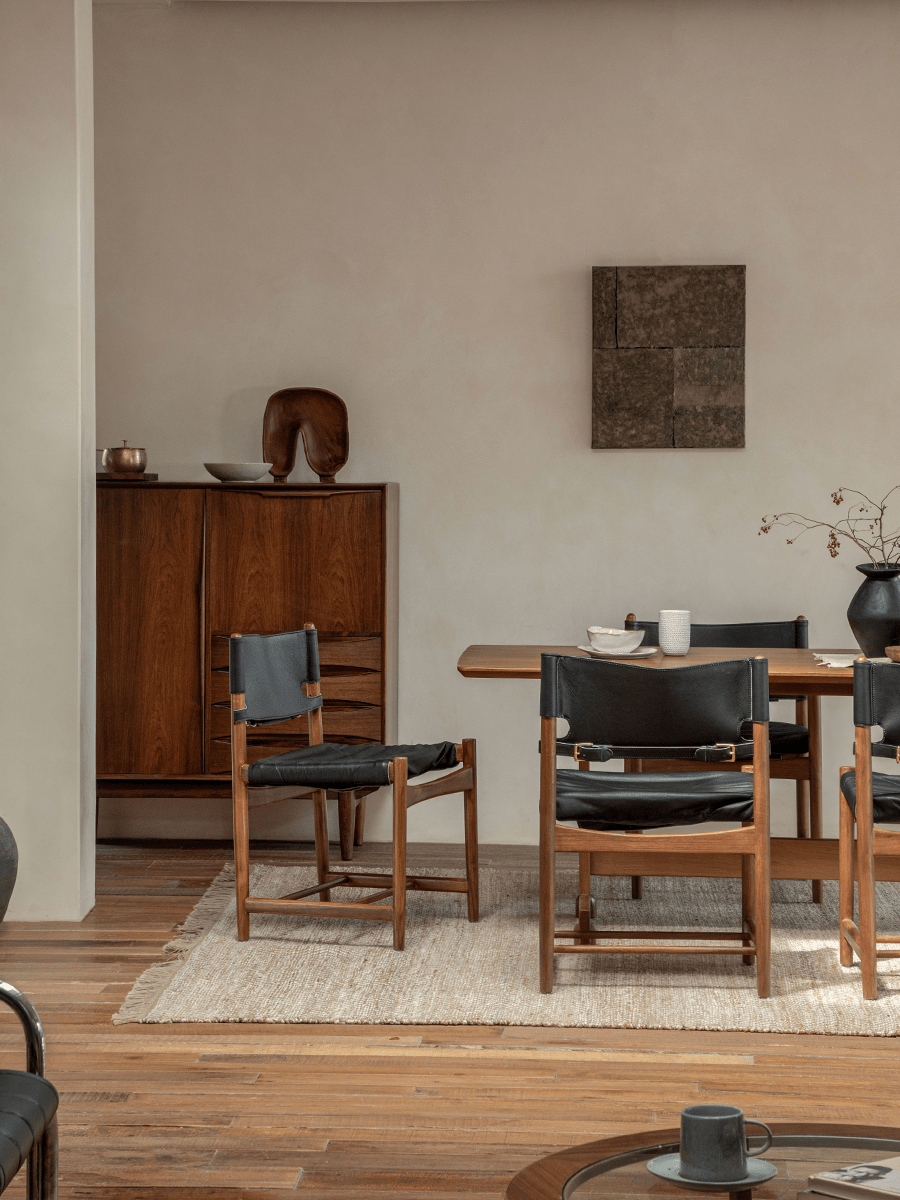 Spanish Dining Chair with black leather seat and teak wood frame in a modern dining room setting