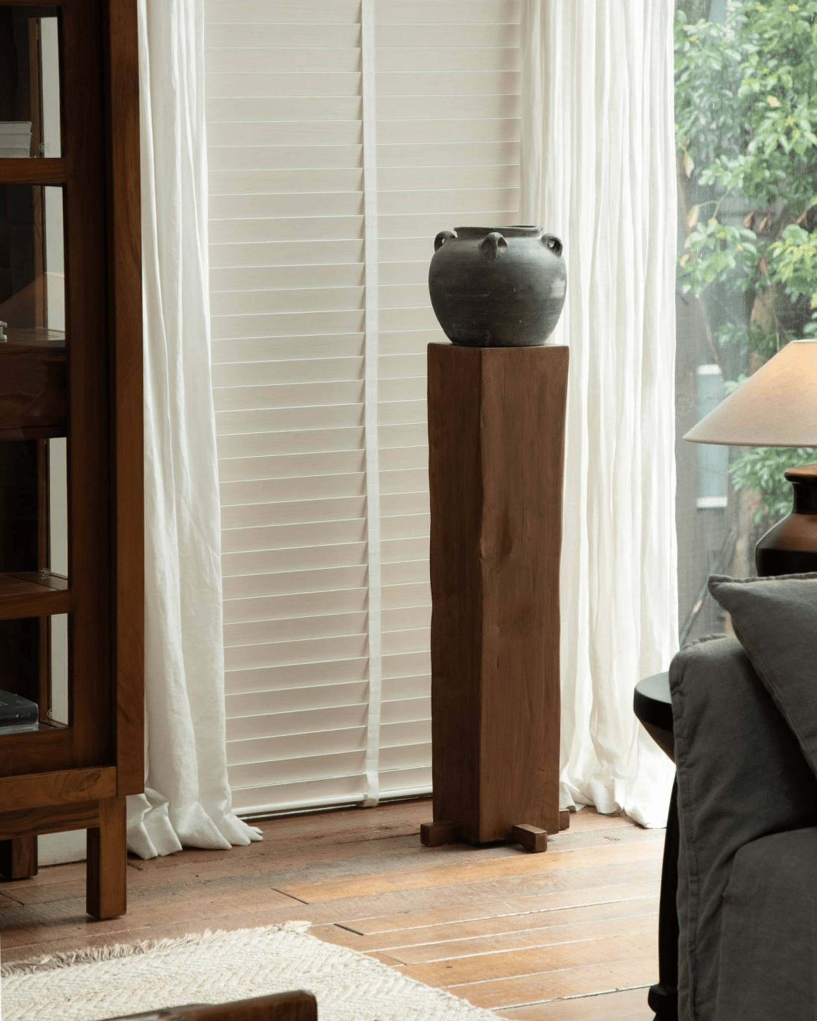 Rustic wooden pedestal with dark vase, organic interior design, natural wood texture, timeless simplicity