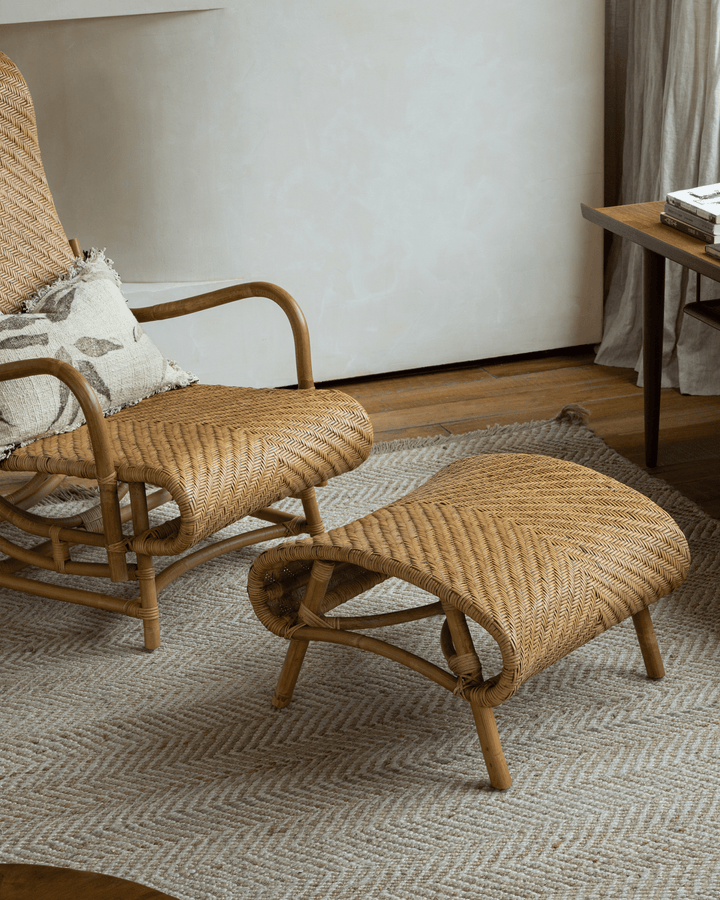 Stylish handwoven rattan lounge chair with ottoman in a cozy living room