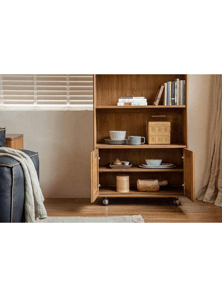 Teak wood display cabinet with open shelves and closed doors, styled with tableware and books.