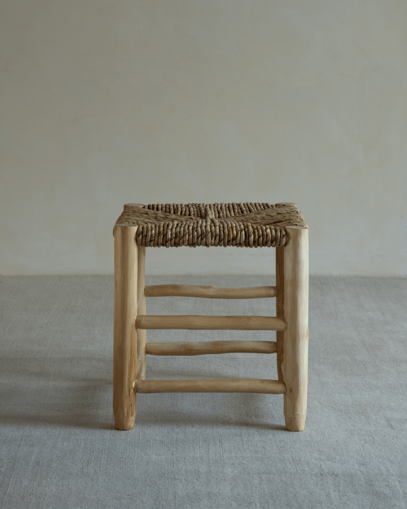 Isla Handwoven Stool showcasing a natural wood frame and woven pandan seat.