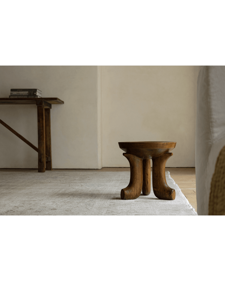 Handcrafted Quincy stool with curved wooden legs in a minimalist living room.