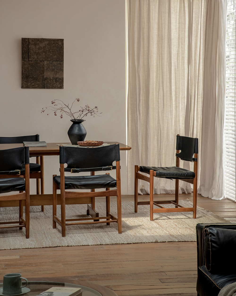 Spanish Dining Chairs with black leather seats and teak wood frames in a neutral dining room setting