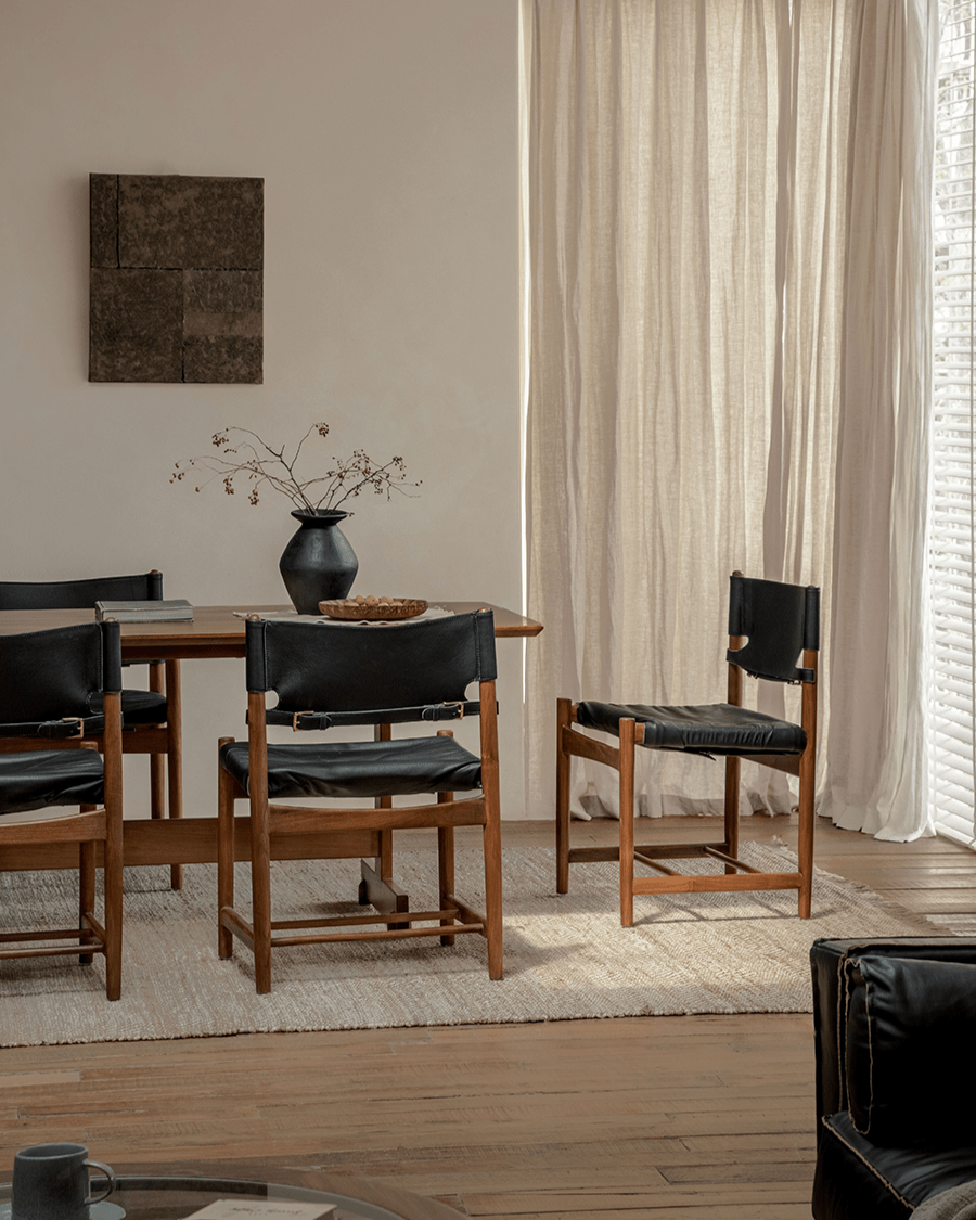 Spanish Dining Chairs with black leather seats and teak wood frames in a neutral dining room setting