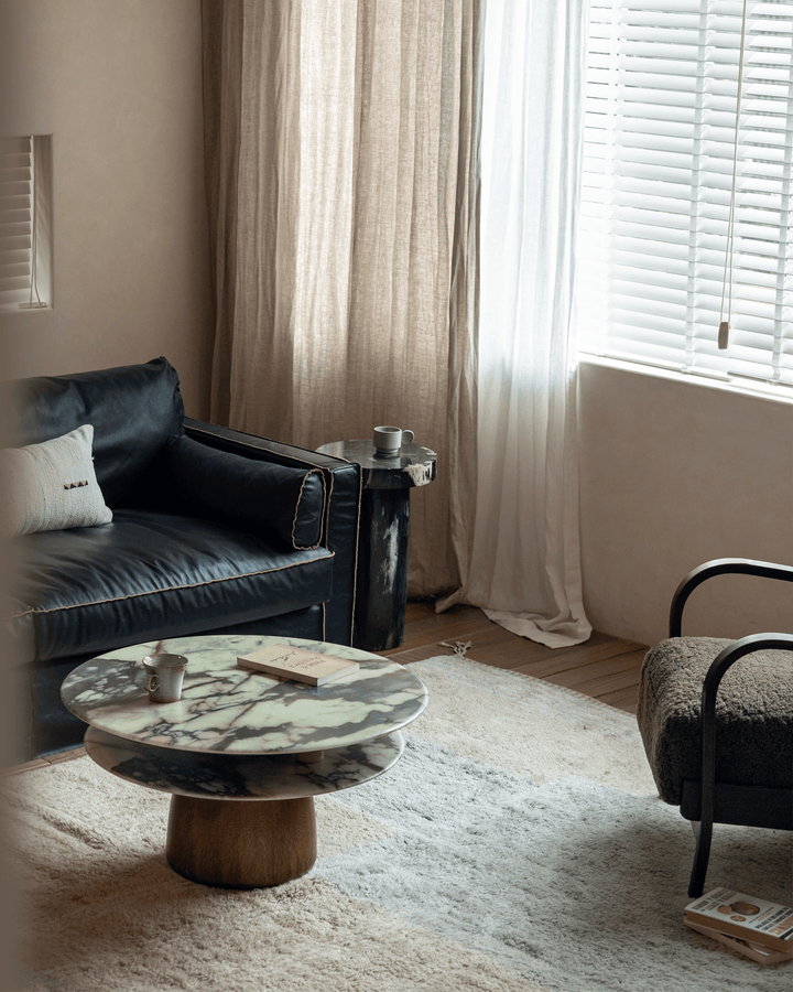 Stylish round table with unique marble top and wooden base in modern living room setting.