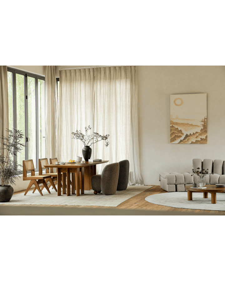 Modern wooden dining table with stylish chairs and decorative vase in bright interior.