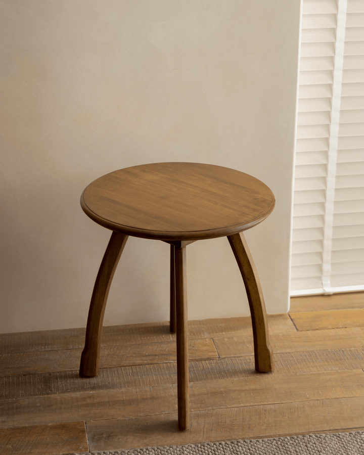 Ele Round Side Table with vintage finish on wooden floor near a bright window