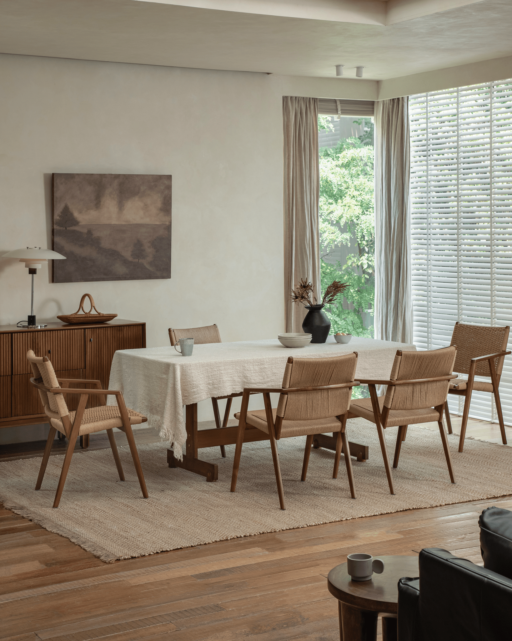 Louisa Chair in a dining room setting. Teak frame, woven seat chairs around table, showcasing Mid-Century Modern design.