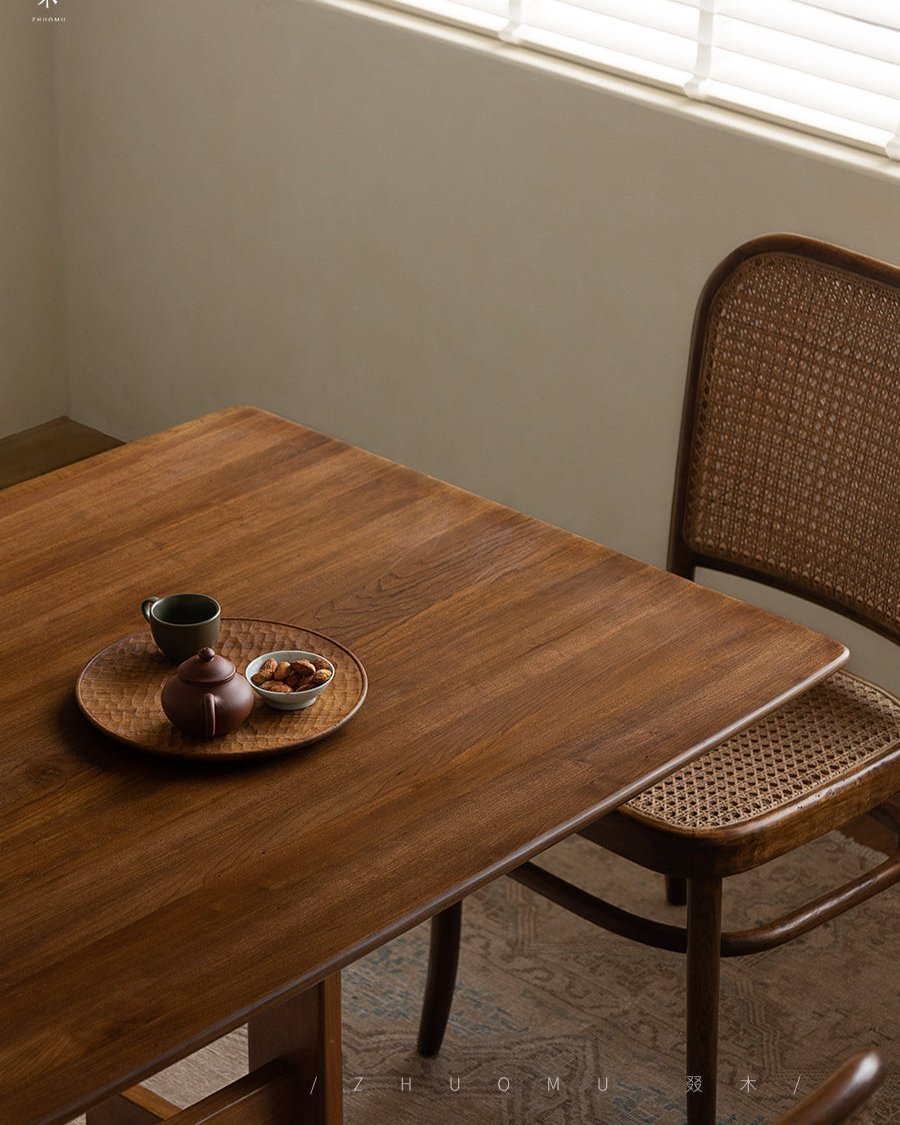 Hoof Dining Table in cozy dining setting. Solid wood with I-shaped base. ZHUOMU brand. Featuring tea set, and wooden chair.