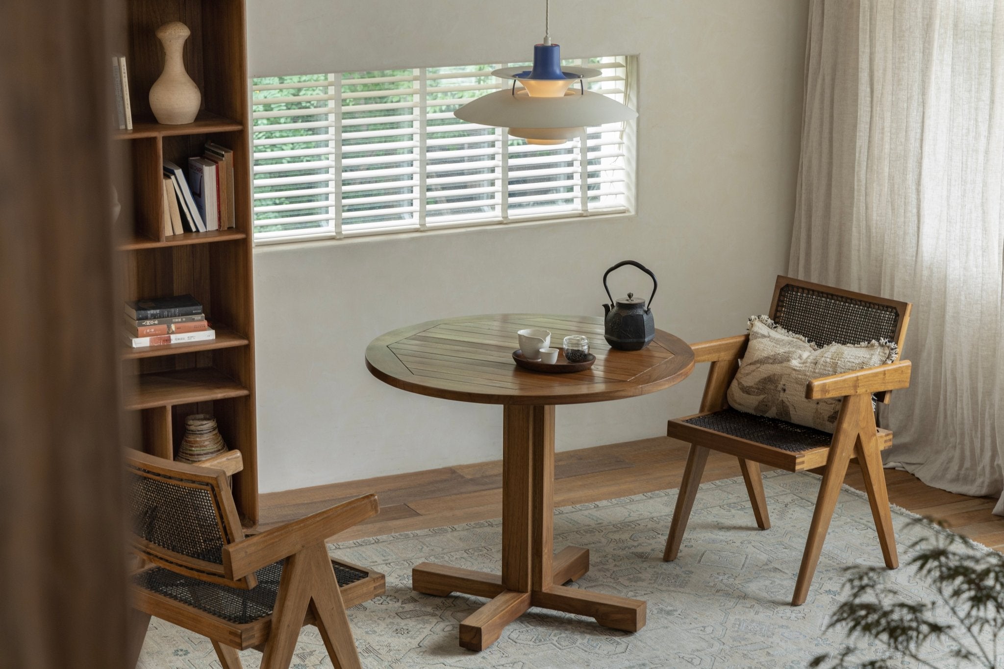 Ruby Round Teak Table in a dining setting. Solid wood table with column leg and matching chairs, perfect for leisure.