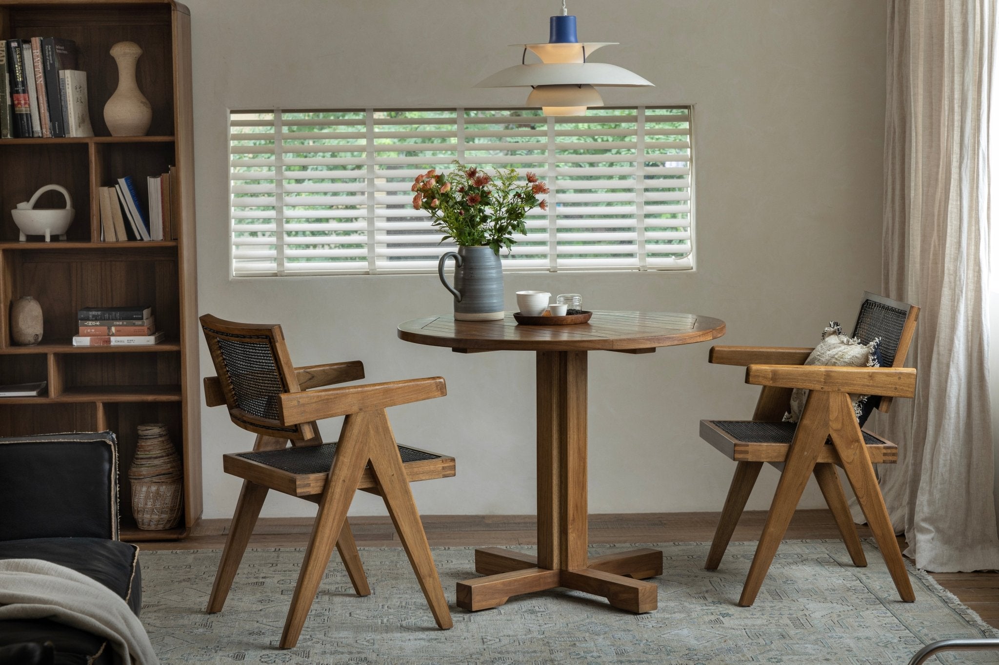 Ruby Teak Round Table in a dining setting with wooden chairs and woven seats
