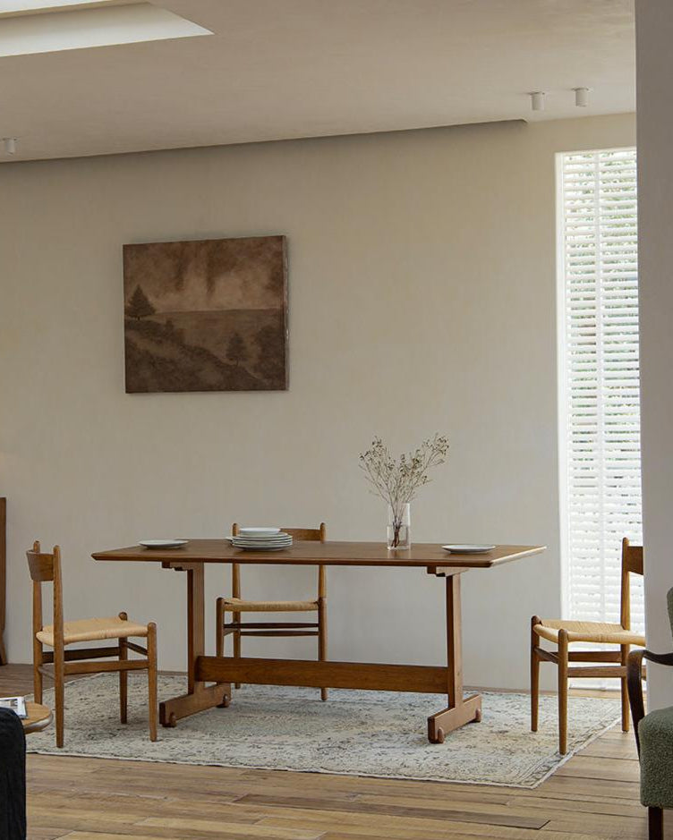 Hoof Dining Table in a cozy dining setting, solid wood, I-shaped base, ZHUOMU brand, wooden chairs and rug.