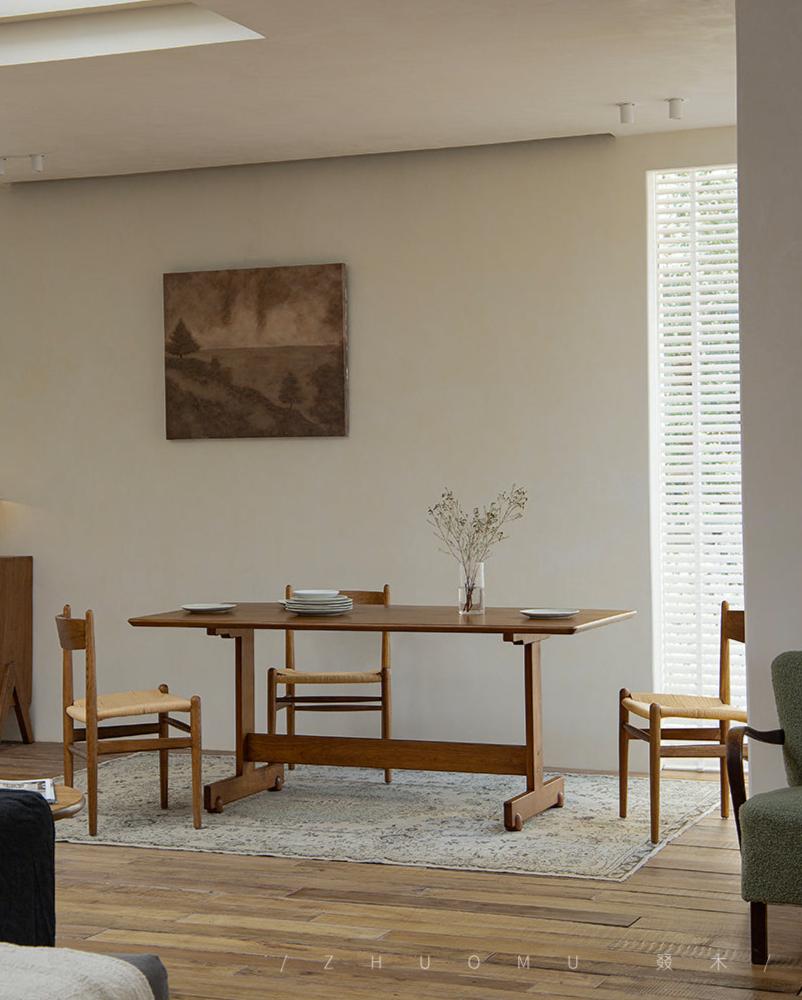 Hoof Dining Table in a cozy dining setting, solid wood, I-shaped base, ZHUOMU brand, wooden chairs and rug.