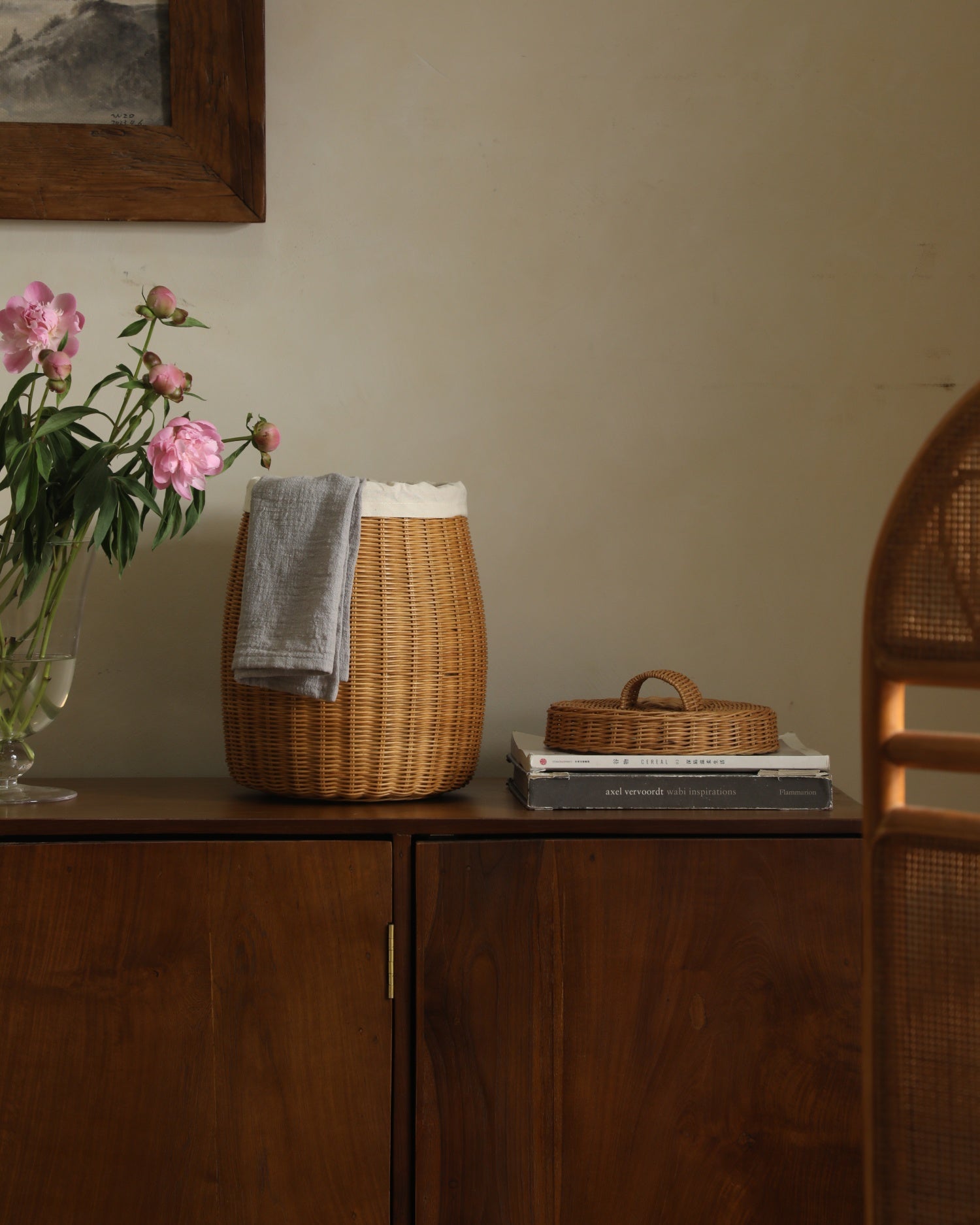 Elodie Round Storage Basket: woven natural rattan with lid and lining, on dark wood cabinet.