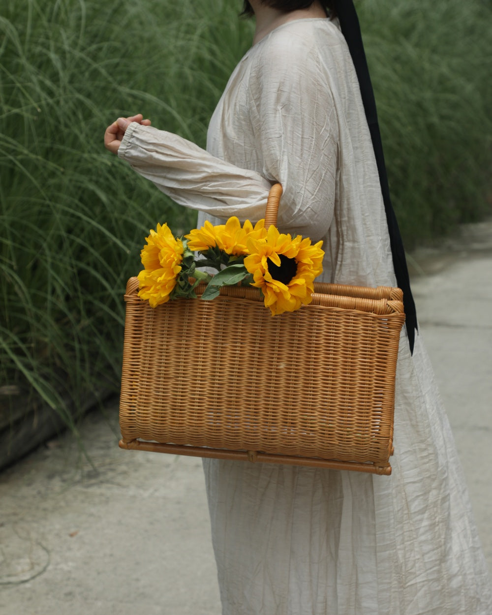 Substantial woven Folio Caddy basket with textured weave holding sunflowers, features integrated handles.