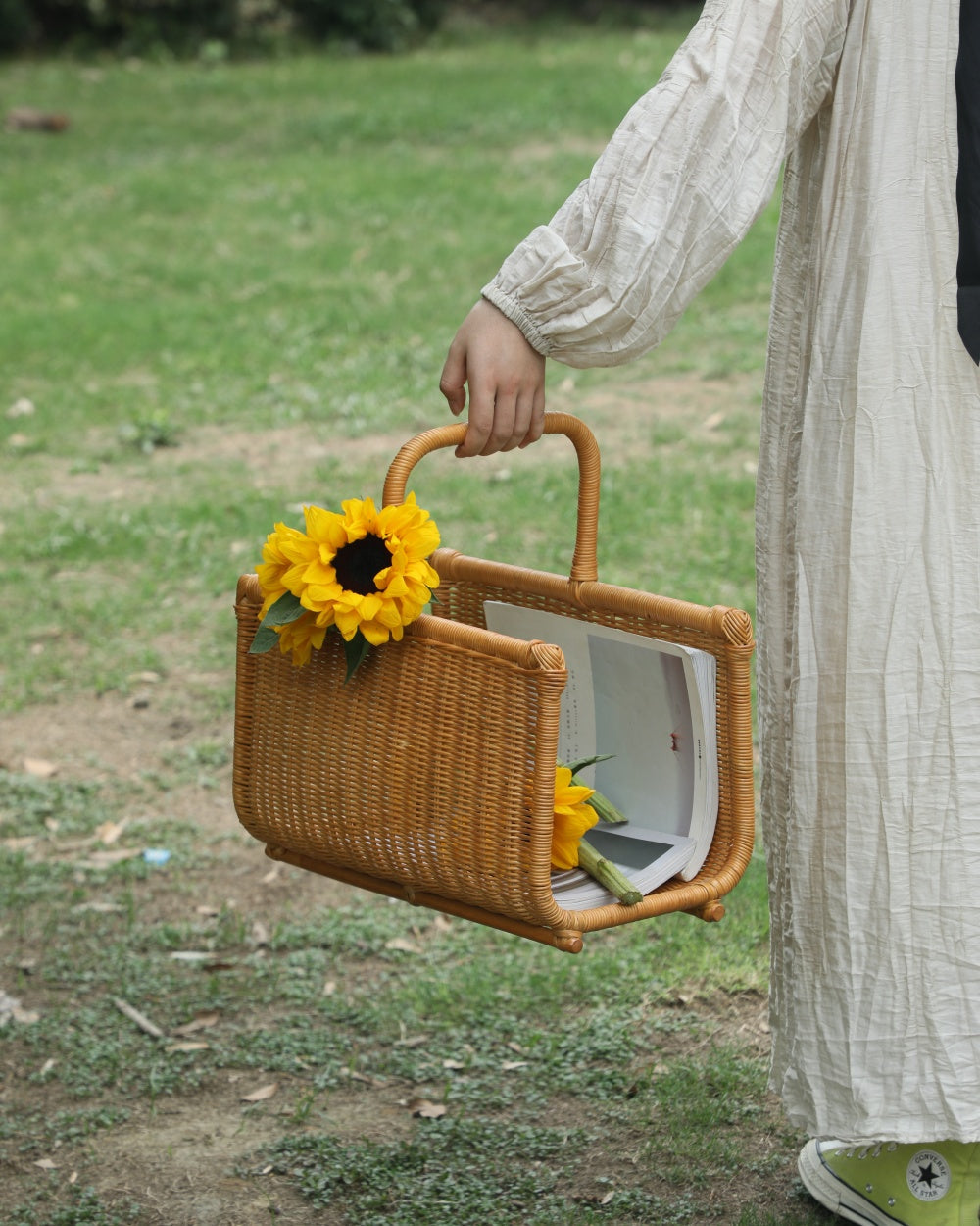Folio Caddy: Textured woven basket with integrated handle, carrying books and sunflowers.