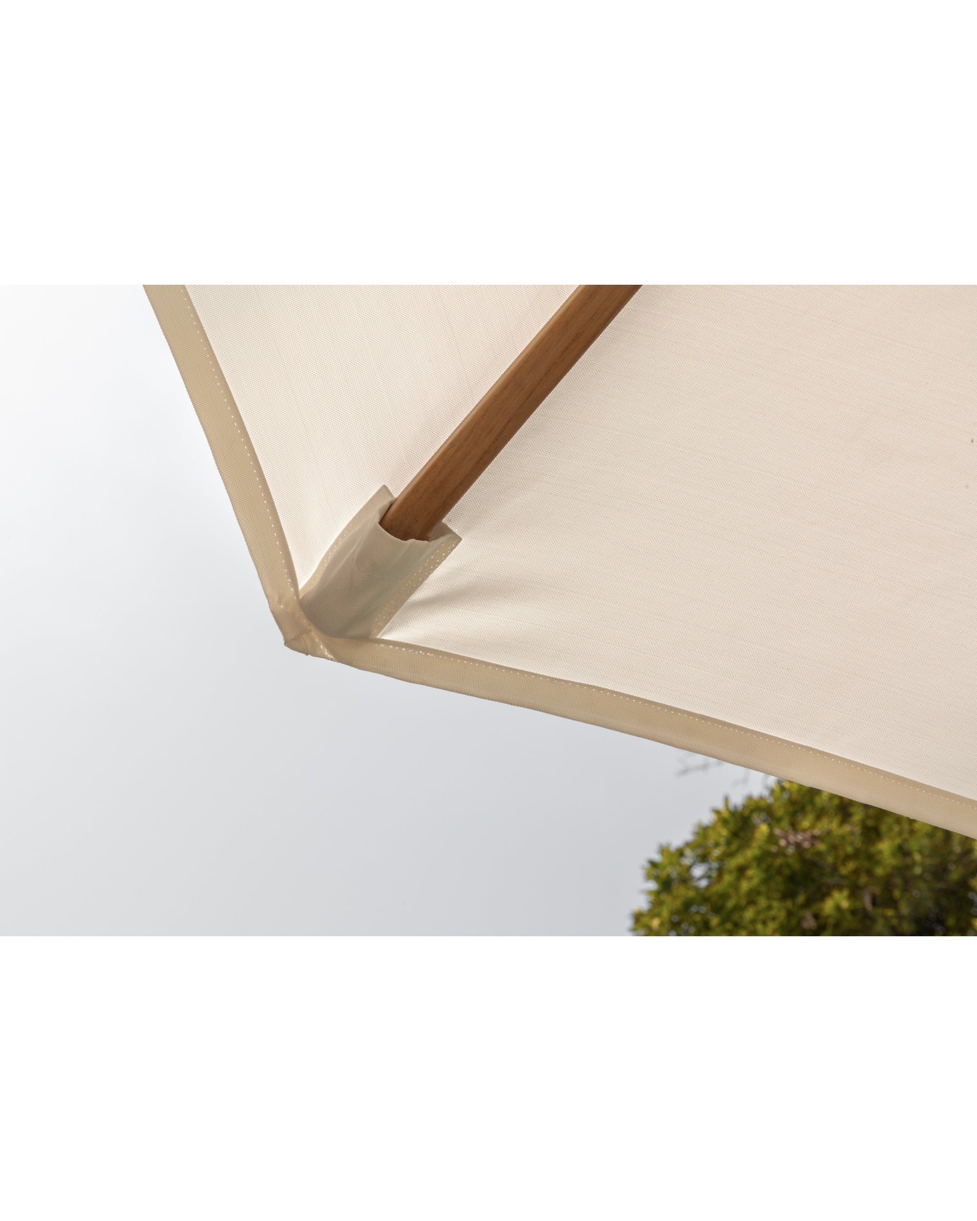 Outdoor umbrella detail: cream acrylic fabric canopy, beige trim, and teak pole.