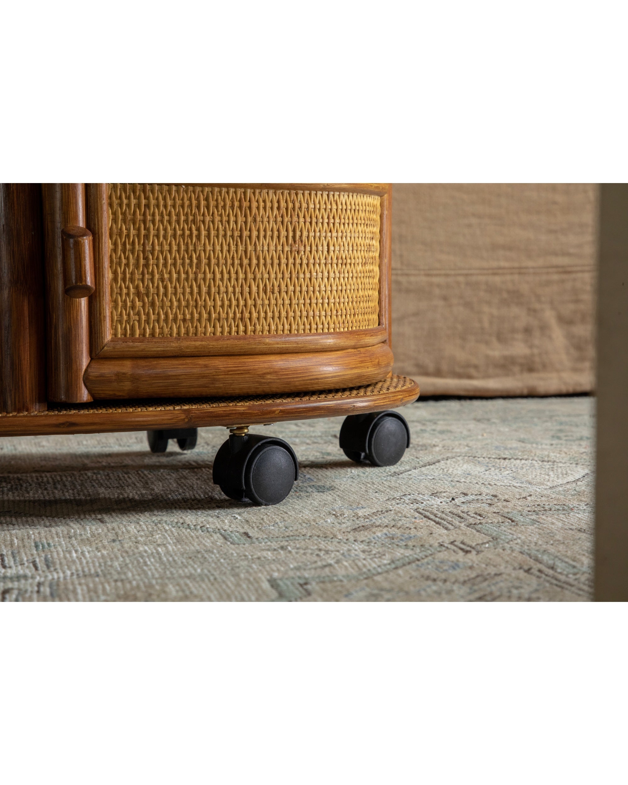 Close-up of Noa Rattan Wheeled Table base with woven rattan and casters