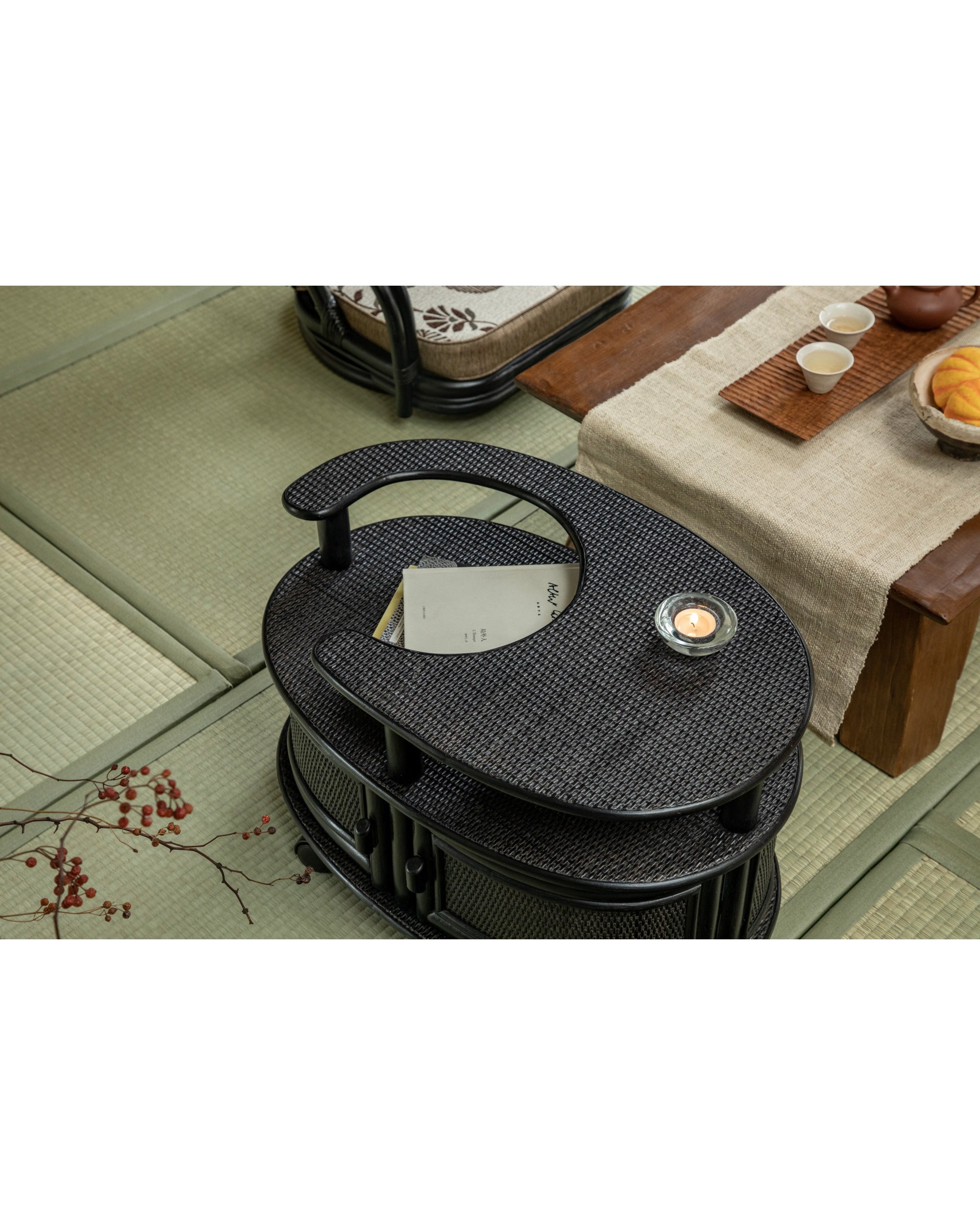 Noa black rattan wheeled table with woven texture and curved design.