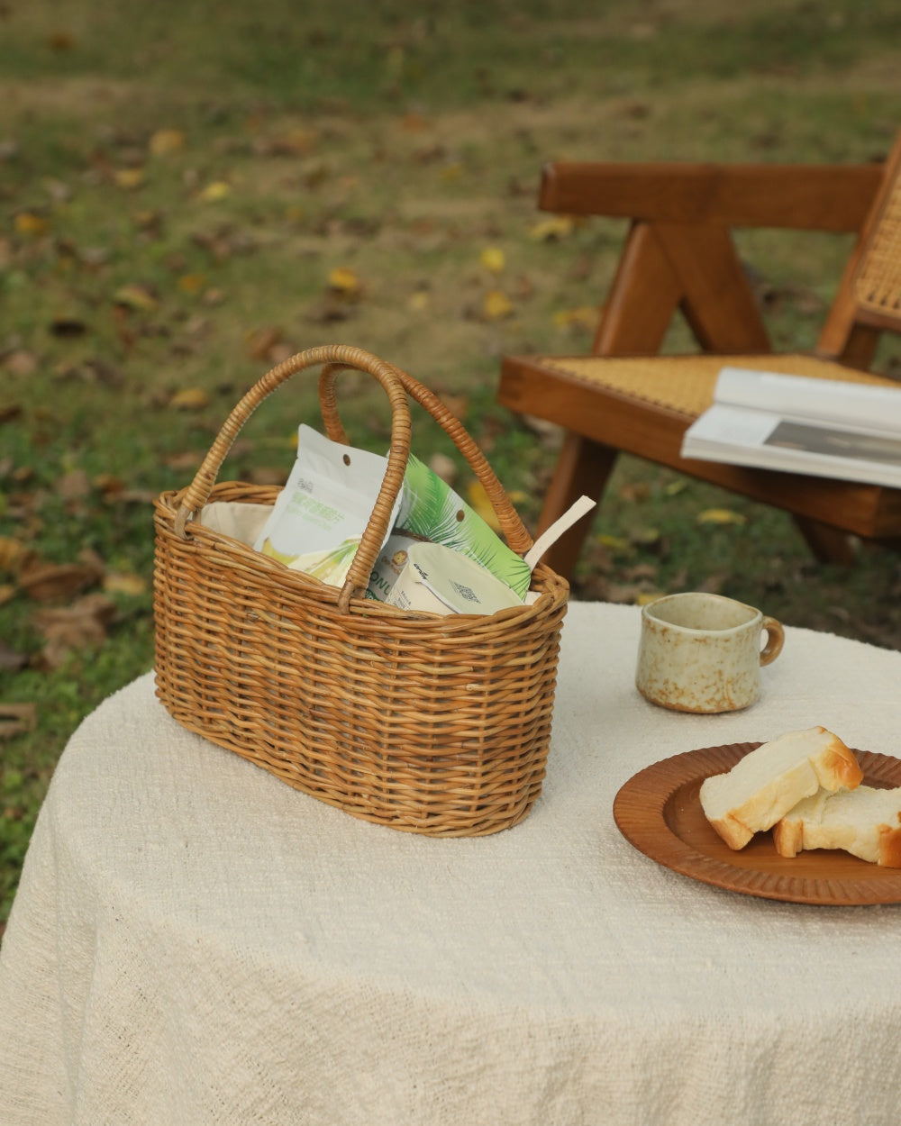 Natural rattan handbag basket with handles, set for a picnic.