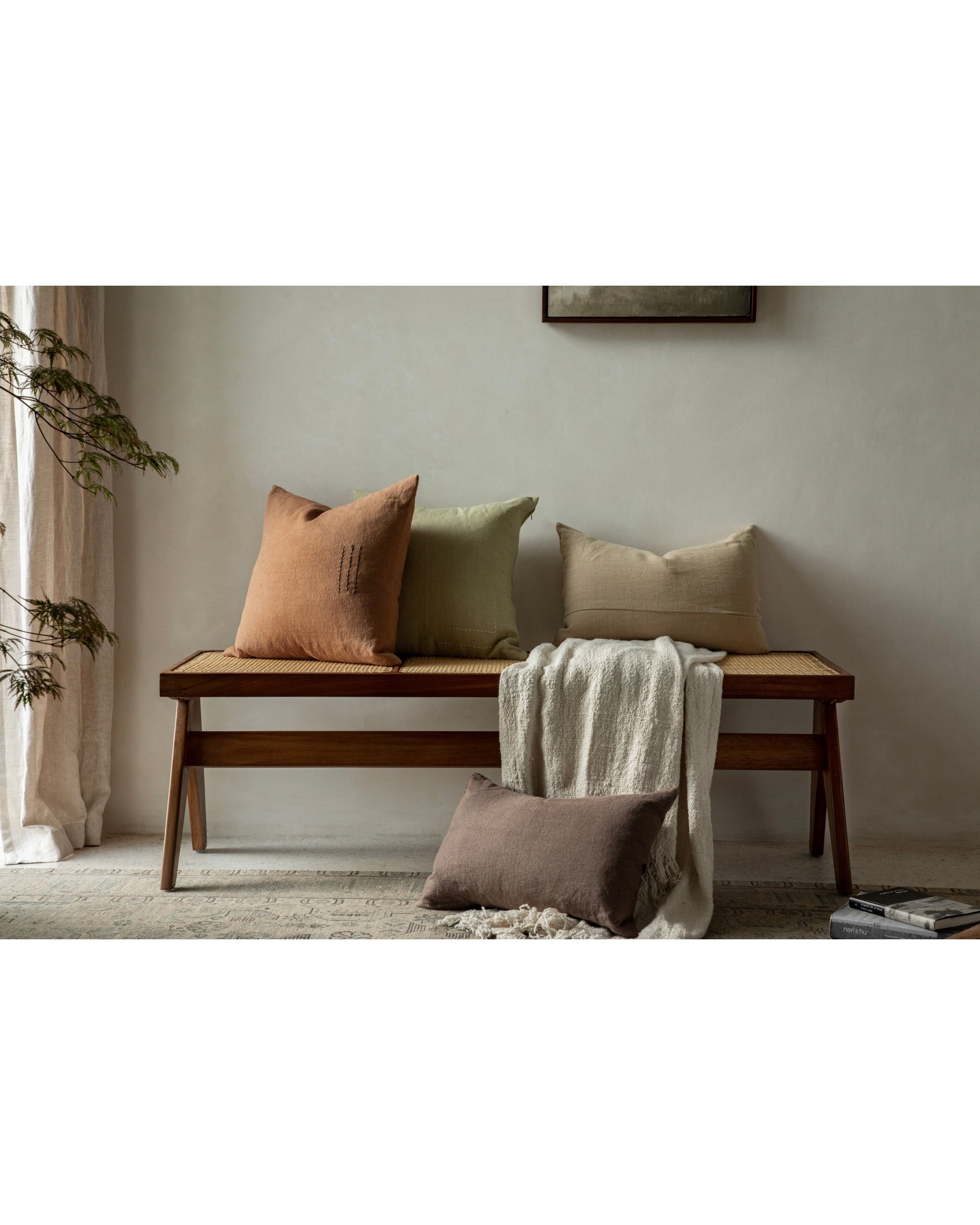 Linora yarn-dyed linen pillows in terracotta, sage, beige, brown on woven bench.