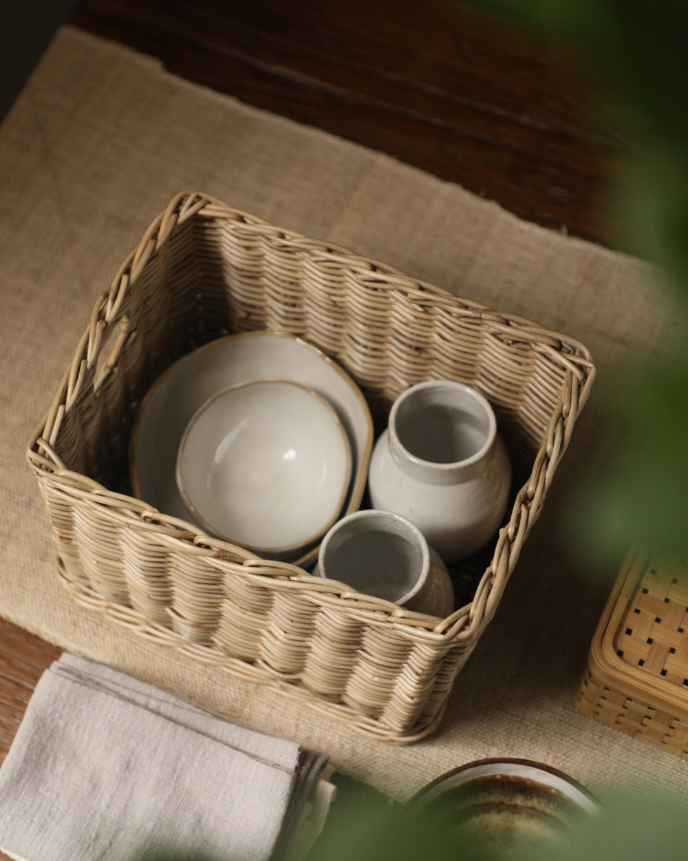 Rectangular hand-woven Loma storage basket in natural fiber, holding dishes and cups