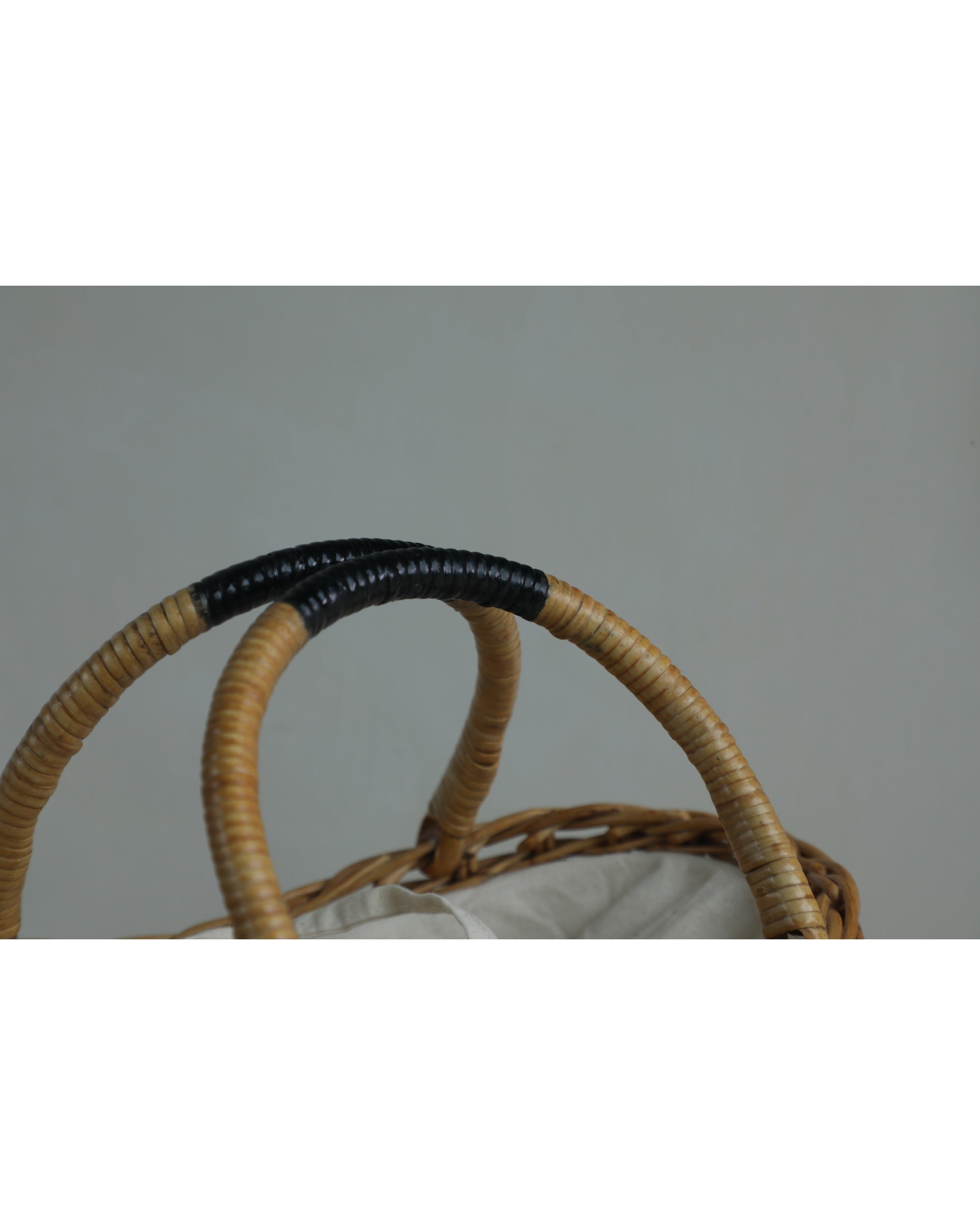 Ivy Hand Bag woven rattan handles with black grip and white lining.