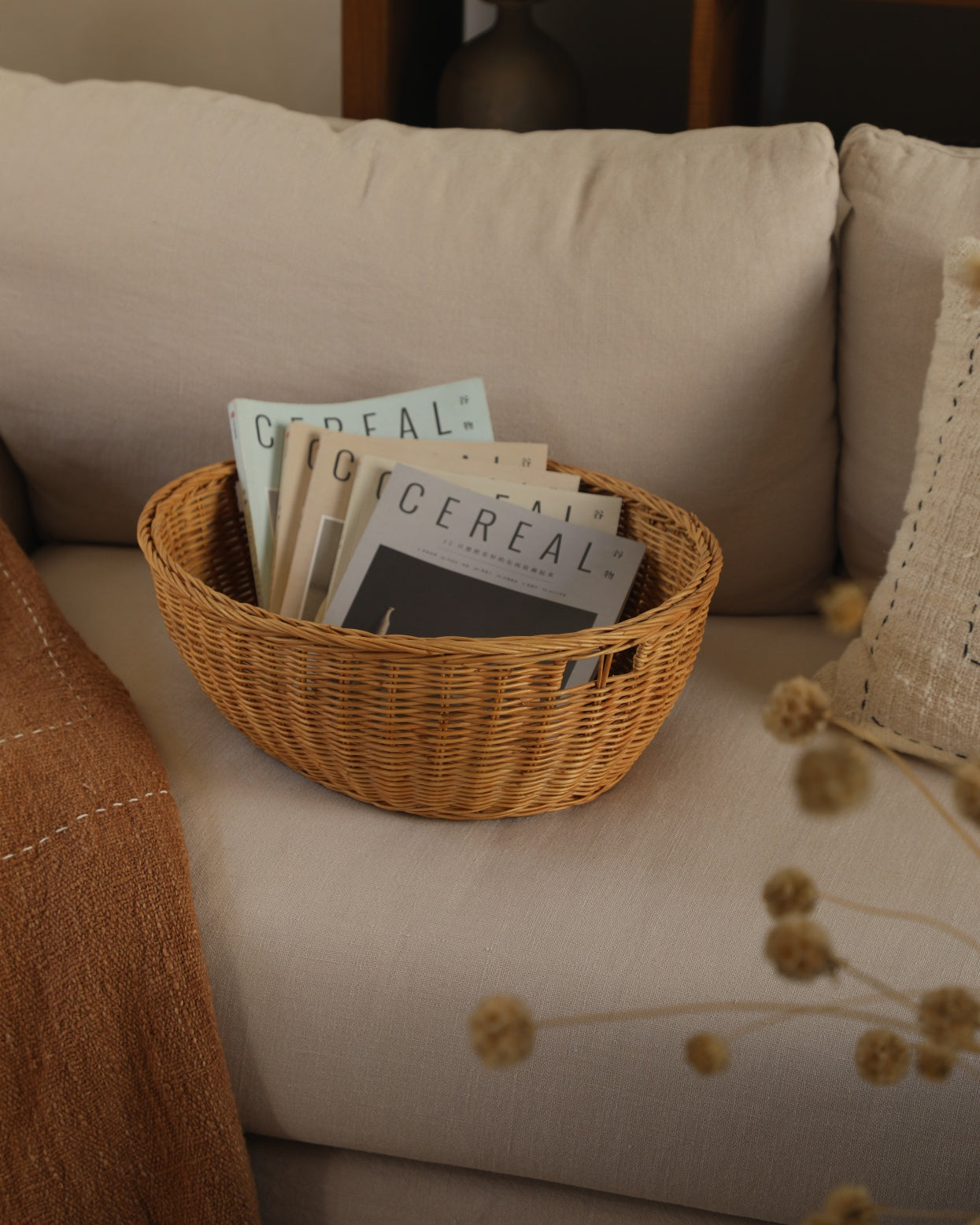 Woven rattan Dottie Basket holding CEREAL magazines on a sofa