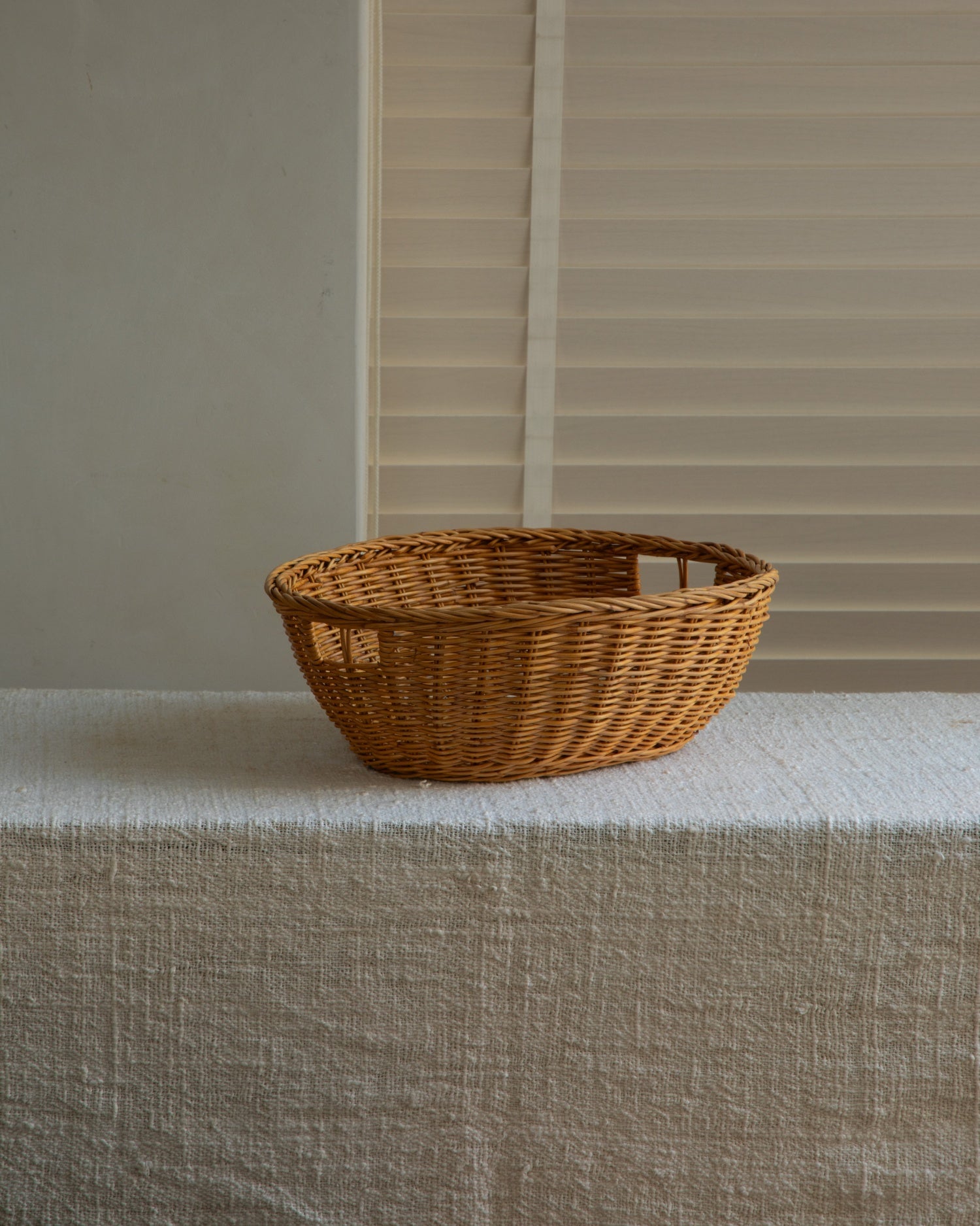 Hand-crafted Dottie oval basket made of natural rattan with a warm, rustic woven texture and side handles.