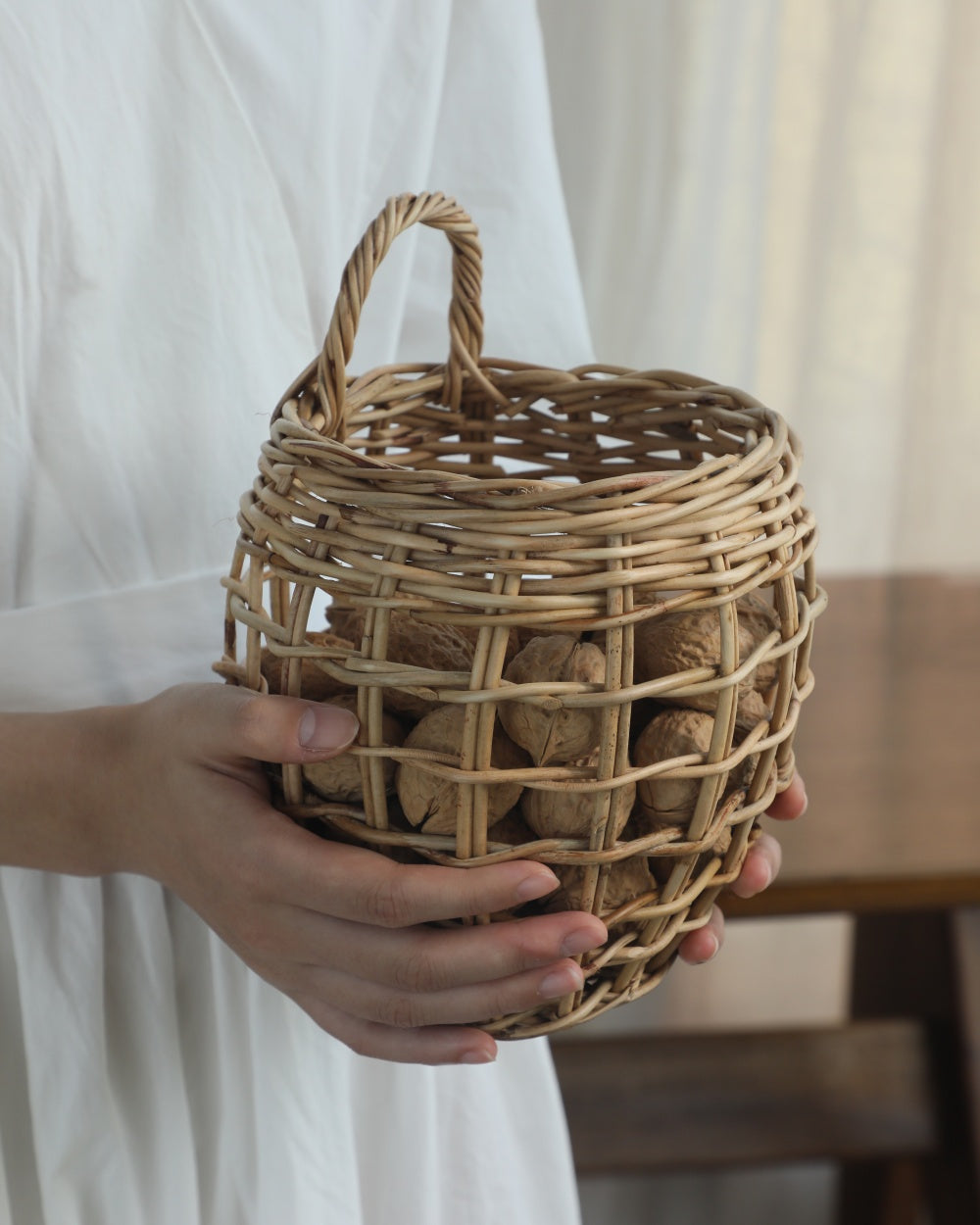 Cove Hanging Basket: Hand-woven natural rattan, deep structure, arched handle, holding walnuts.