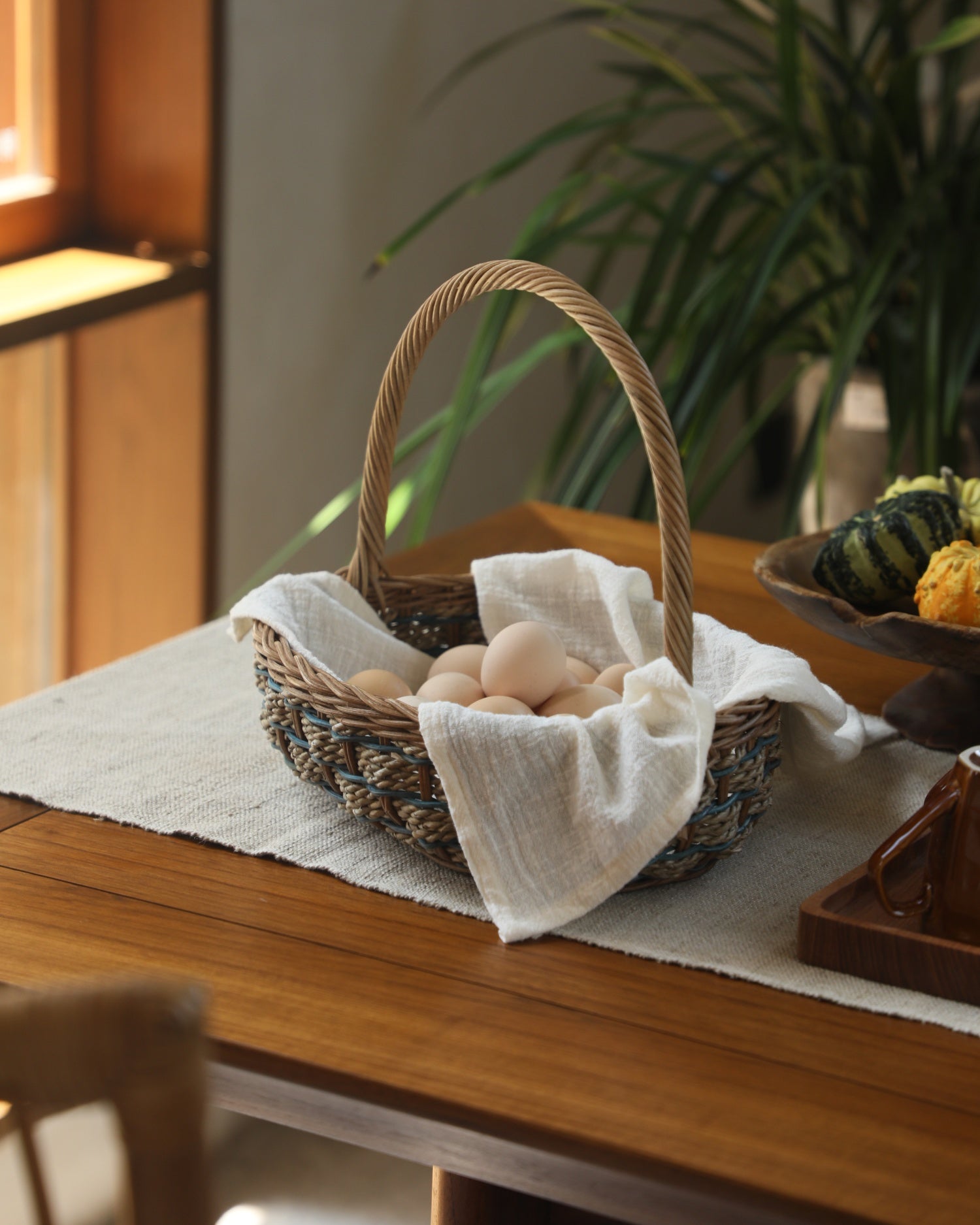 Viney Tote Basket woven with blue and natural rattan, lined with white cloth.
