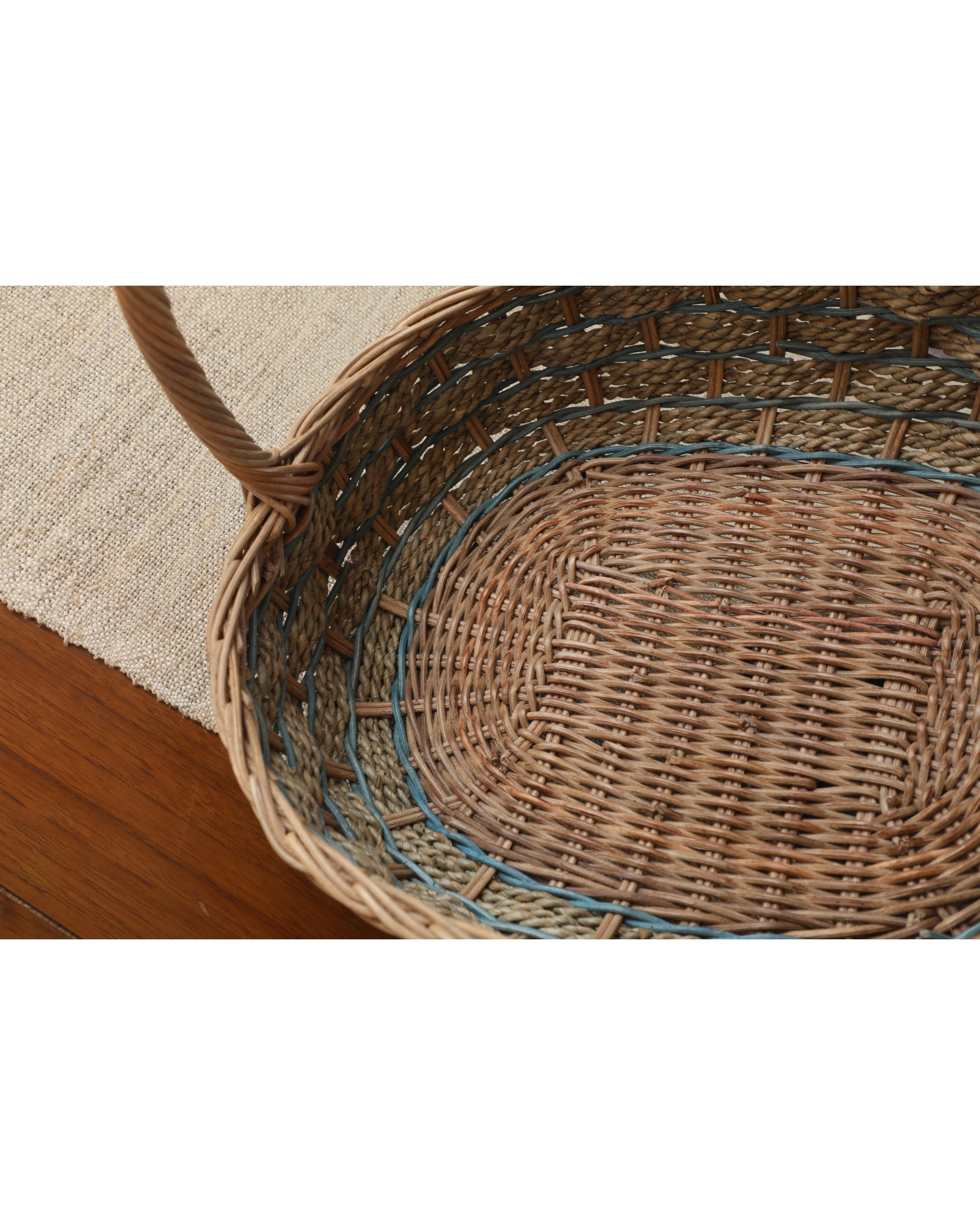 Viney oval woven rattan basket with subtle blue accents and a sturdy twisted handle.