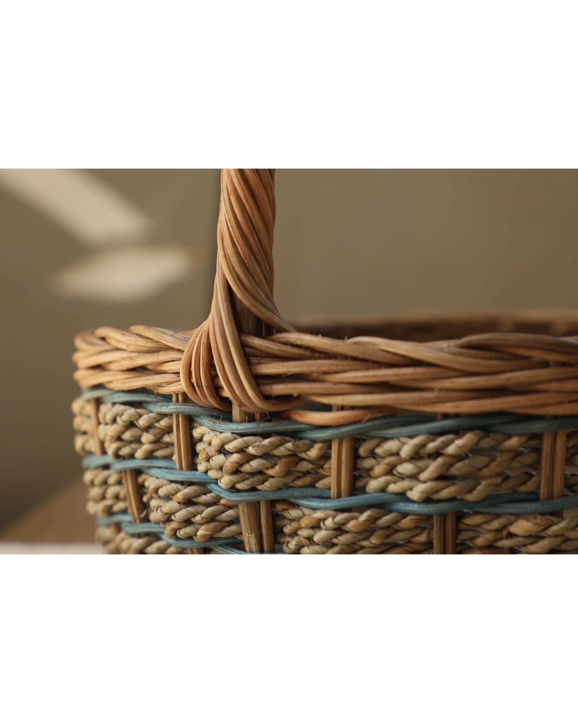 Viney Tote Basket crafted from woven natural rattan with blue accents and handle.
