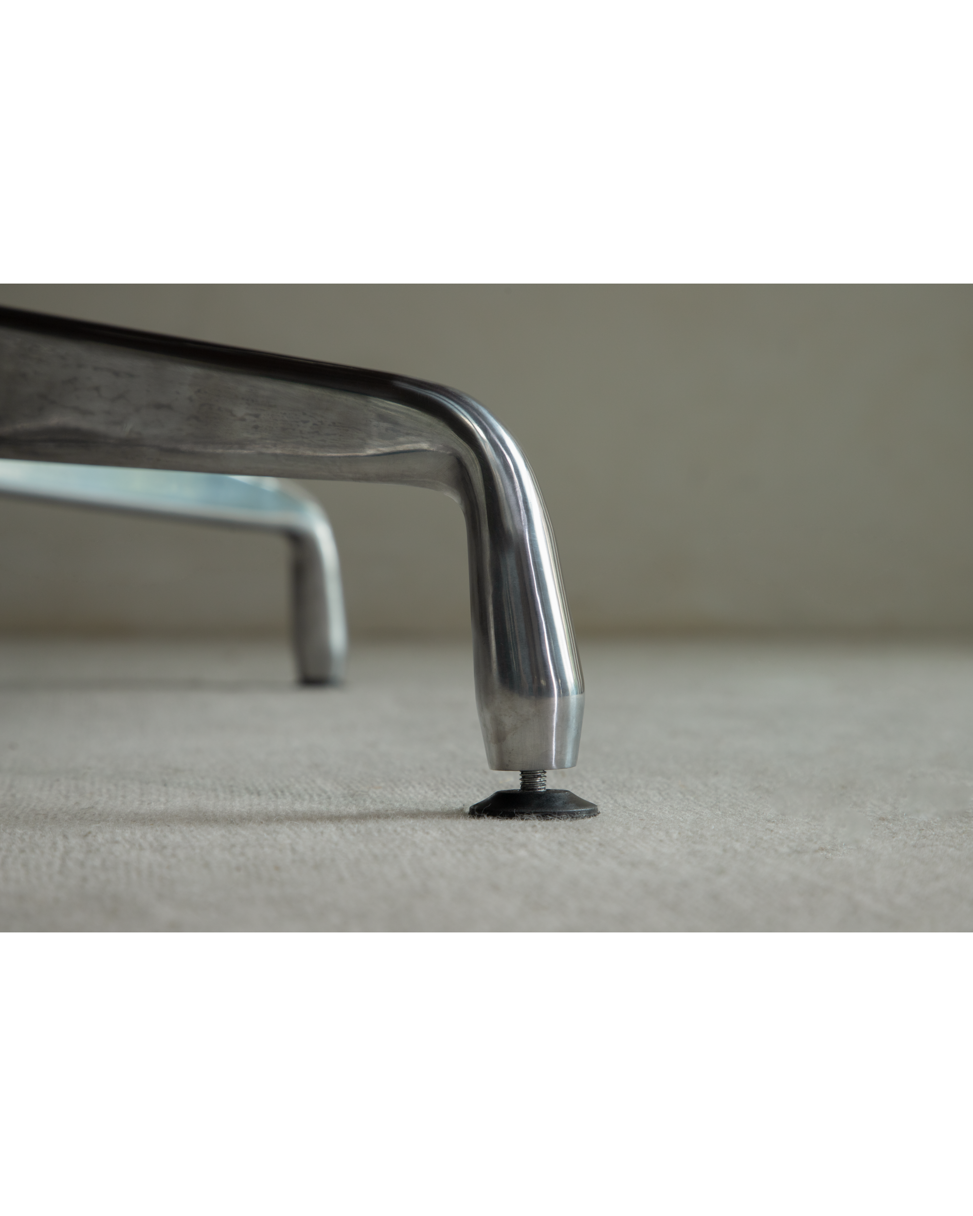 Close-up of adjustable black foot on polished aluminum alloy leg of Evan Office Desk.