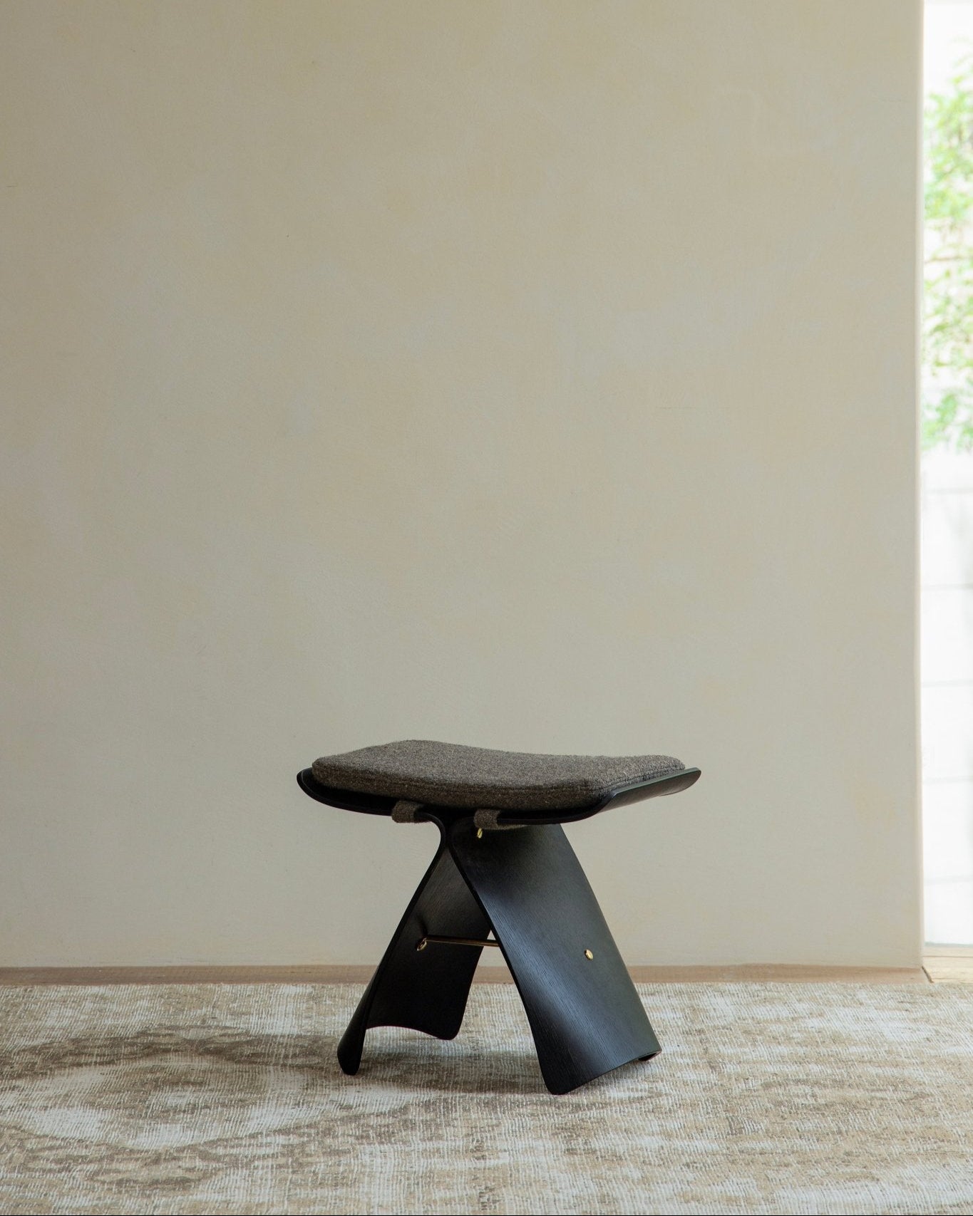 Carbonized Black Butterfly Stool with gray cushion, modern design, solid wood bending construction, elegant interior design