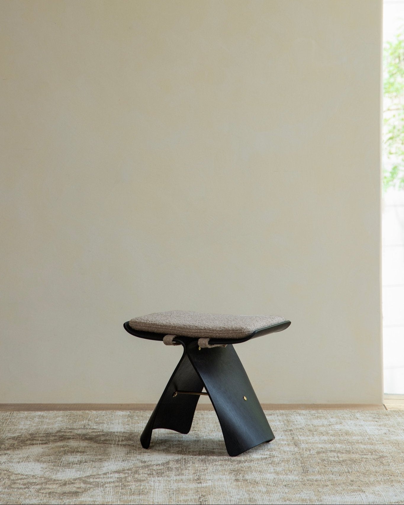 Carbonized Black Butterfly Stool with neutral cushion, modern interior design, solid wood bending construction