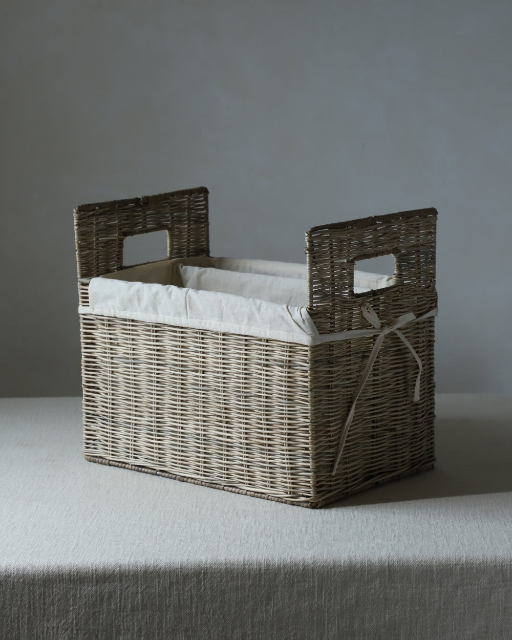 Elara natural rattan storage basket with cotton lining and cut-out handles.
