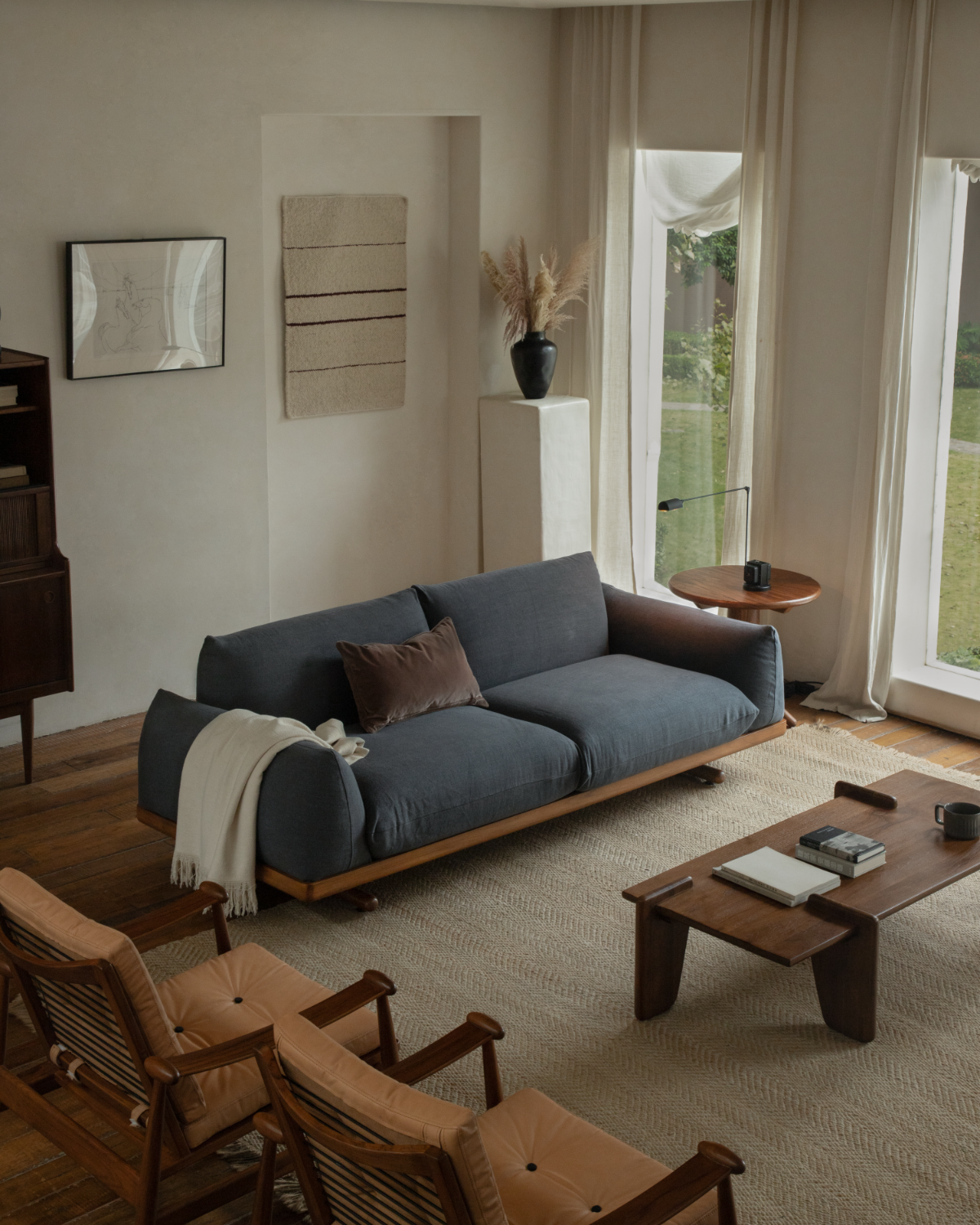 Adrian Sofa in dark linen with teak wood base in a warm modern living room
