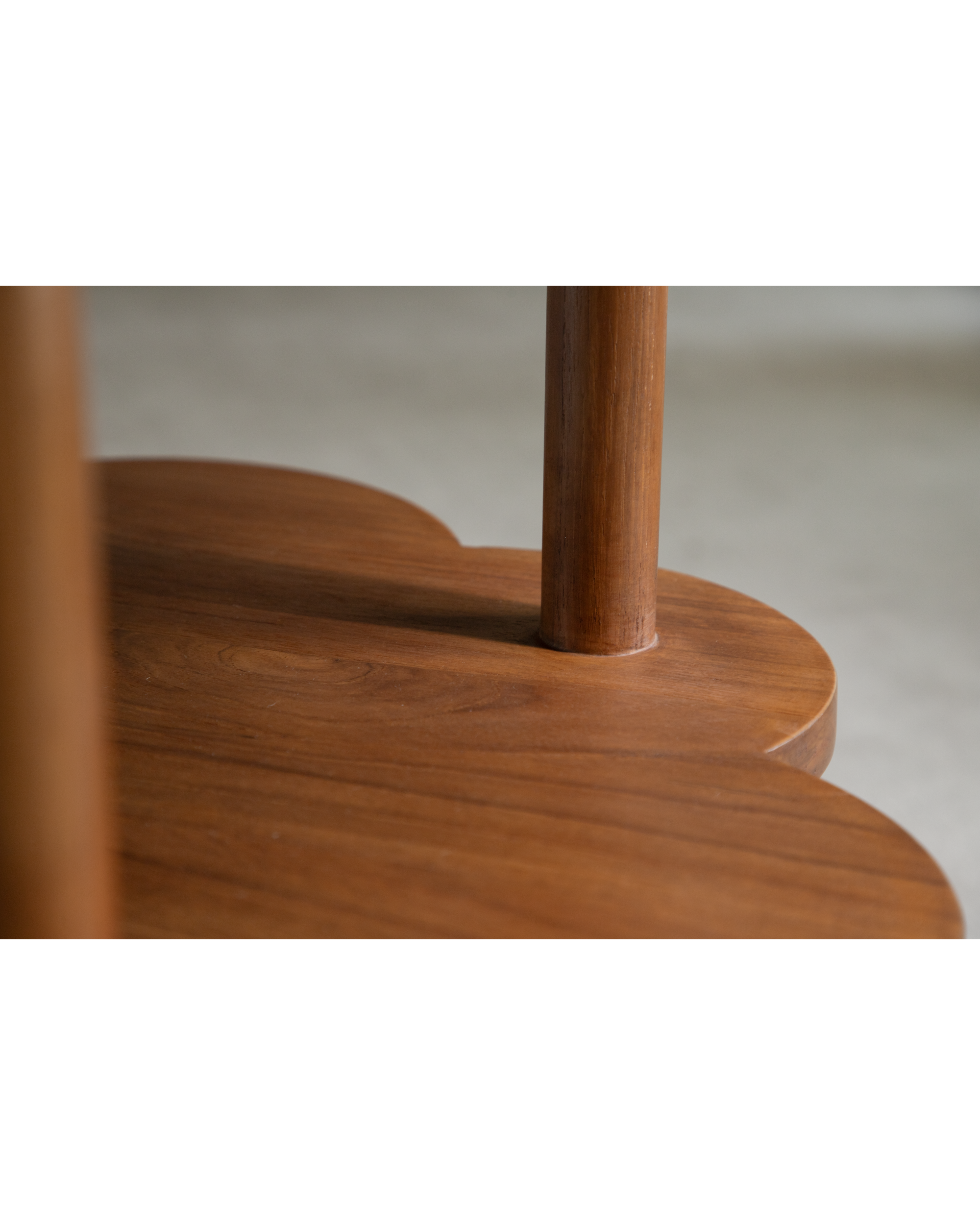 Daisy Side Table detail: solid teak wood leg integrated into scalloped tabletop edge.