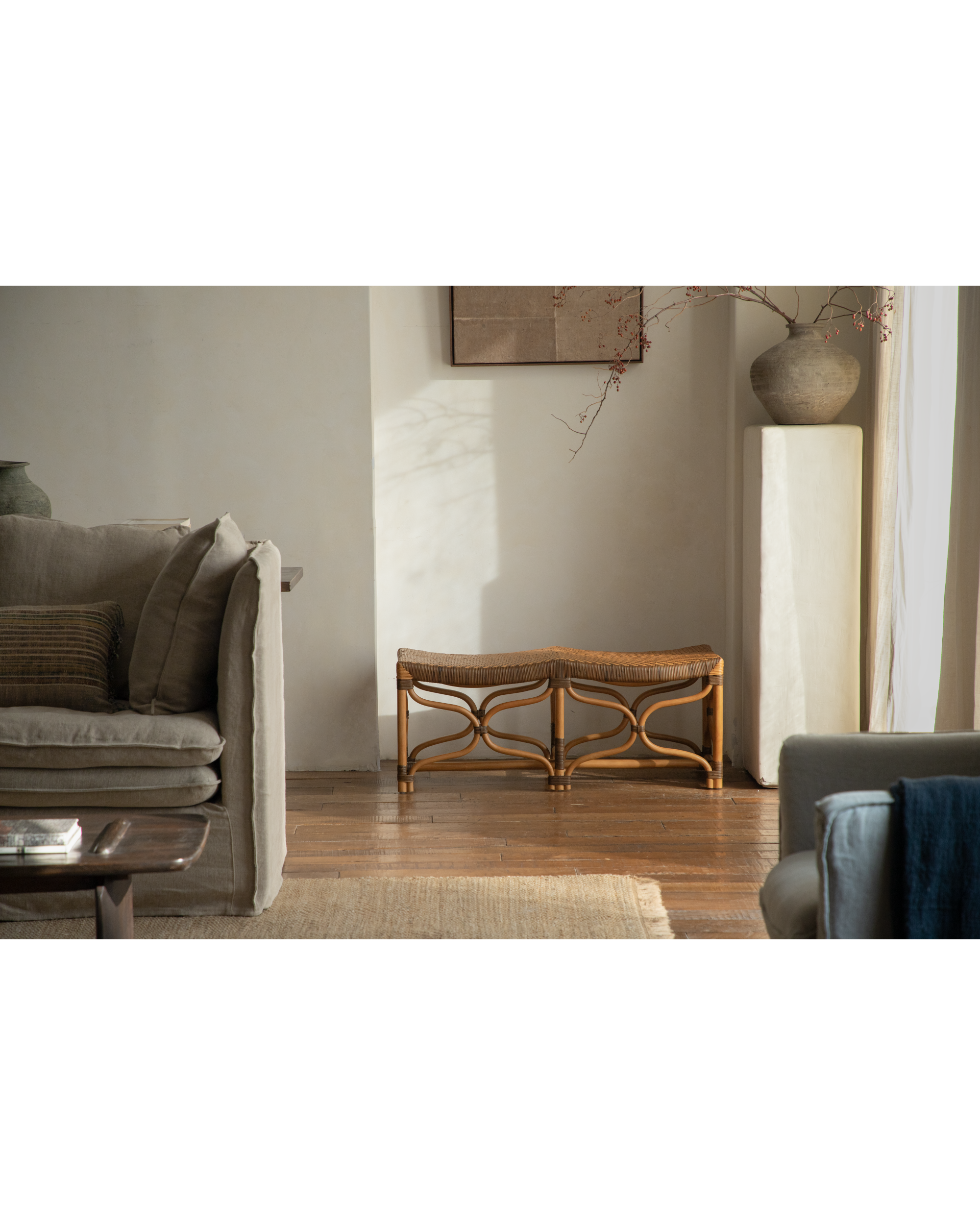 Melange rattan bench with wave-shaped woven seat and curved openwork legs in a neutral living room