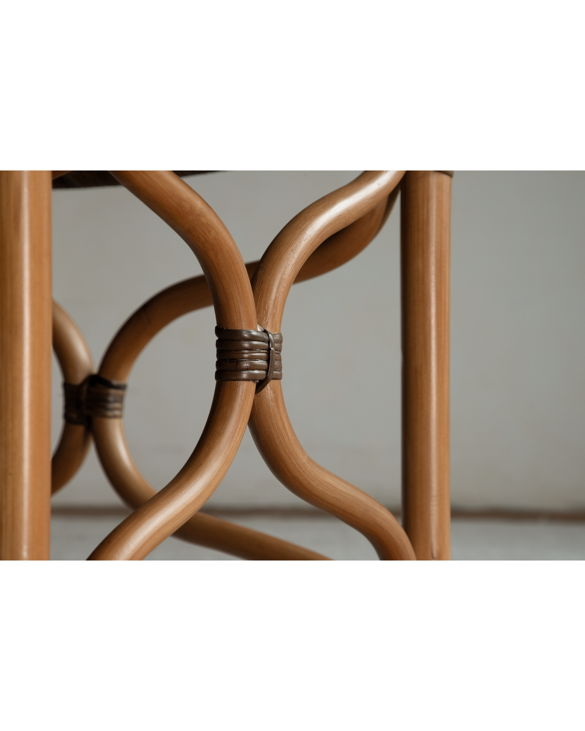 Curved rattan bench leg detail with woven joint and warm natural wood finish