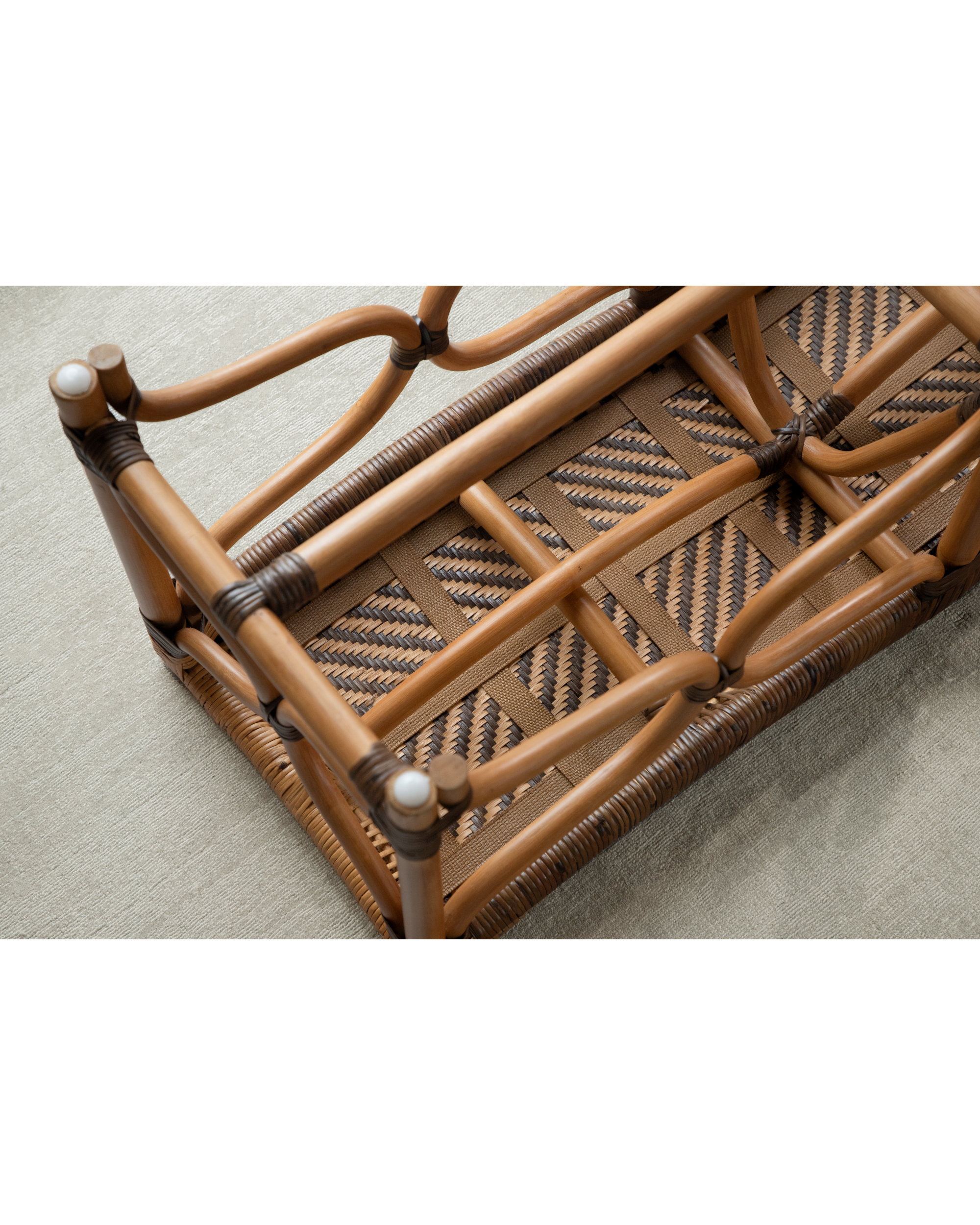 Underside of a melange rattan bench showing woven seat, curved frame, and dark binding details