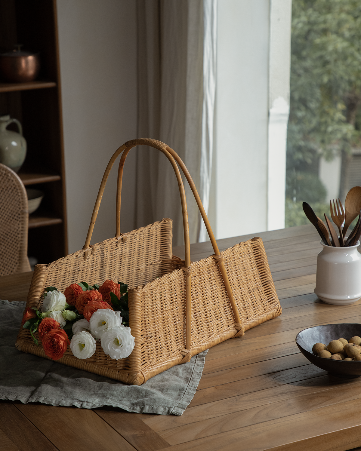 June Basket: Hand-woven natural rattan basket with concave silhouette, holding roses.