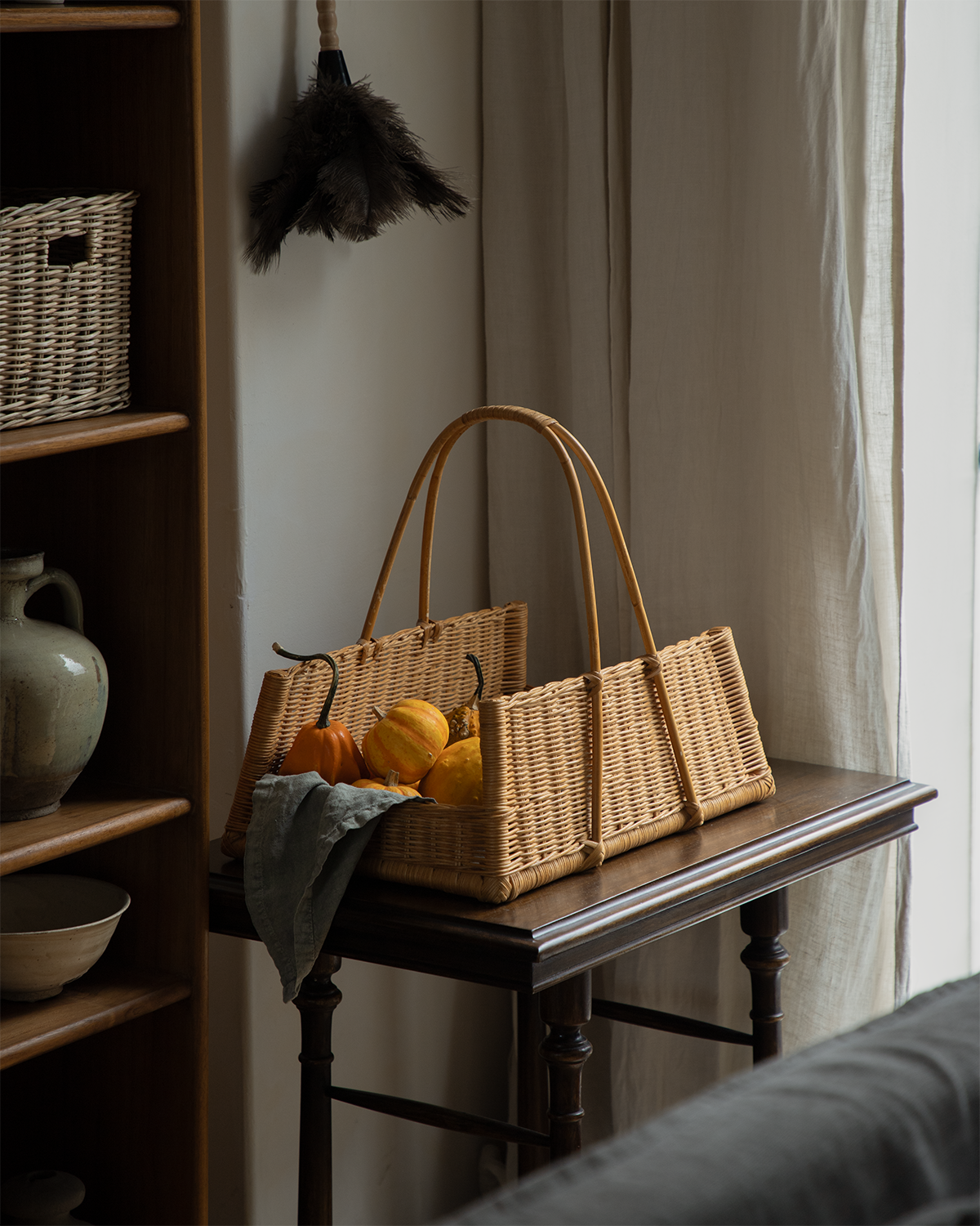 Hand-woven natural rattan June Basket with concave silhouette, holding decorative pumpkins