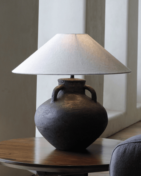 Ear lamp with clay jug base and beige shade on wooden table