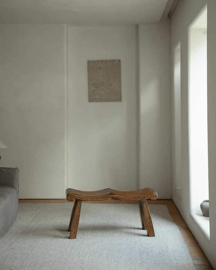 Tildes bench with wavy wooden seat in a minimalist living room space.