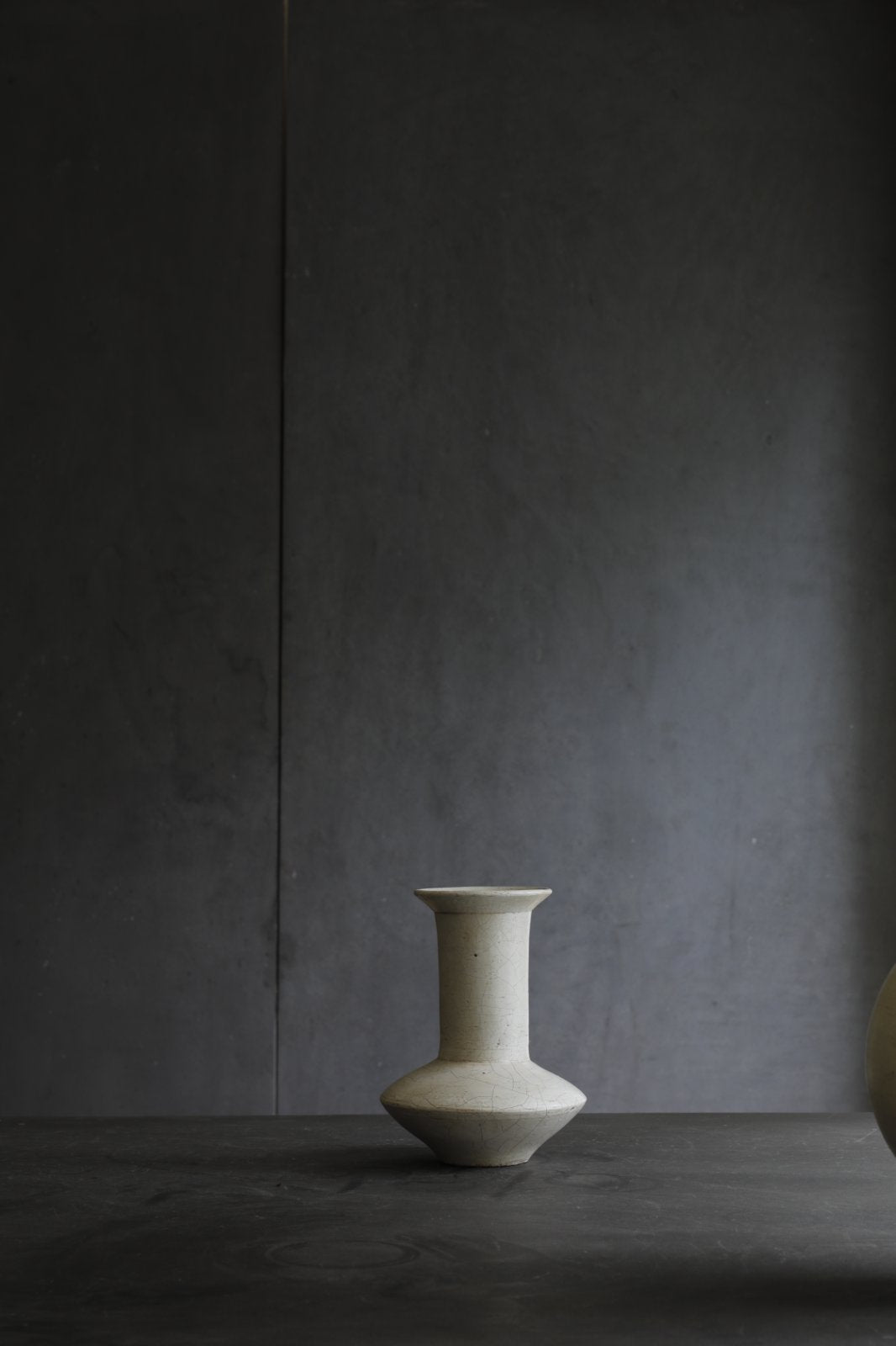 Off-white ceramic vase, minimalist design for home decor. Features a wide base, a narrow neck, and a flared rim.