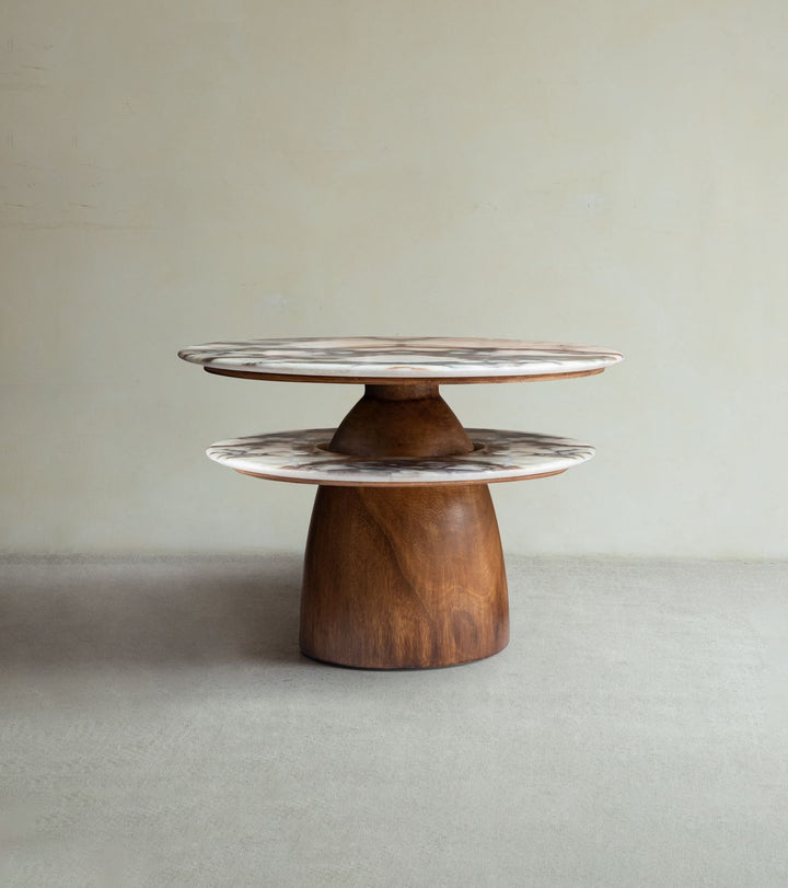 The Dorothy Side Table by ZM Home showcases a round wooden design with marble-like surfaces at varying heights and a solid rain wood base, all set against a plain beige background.