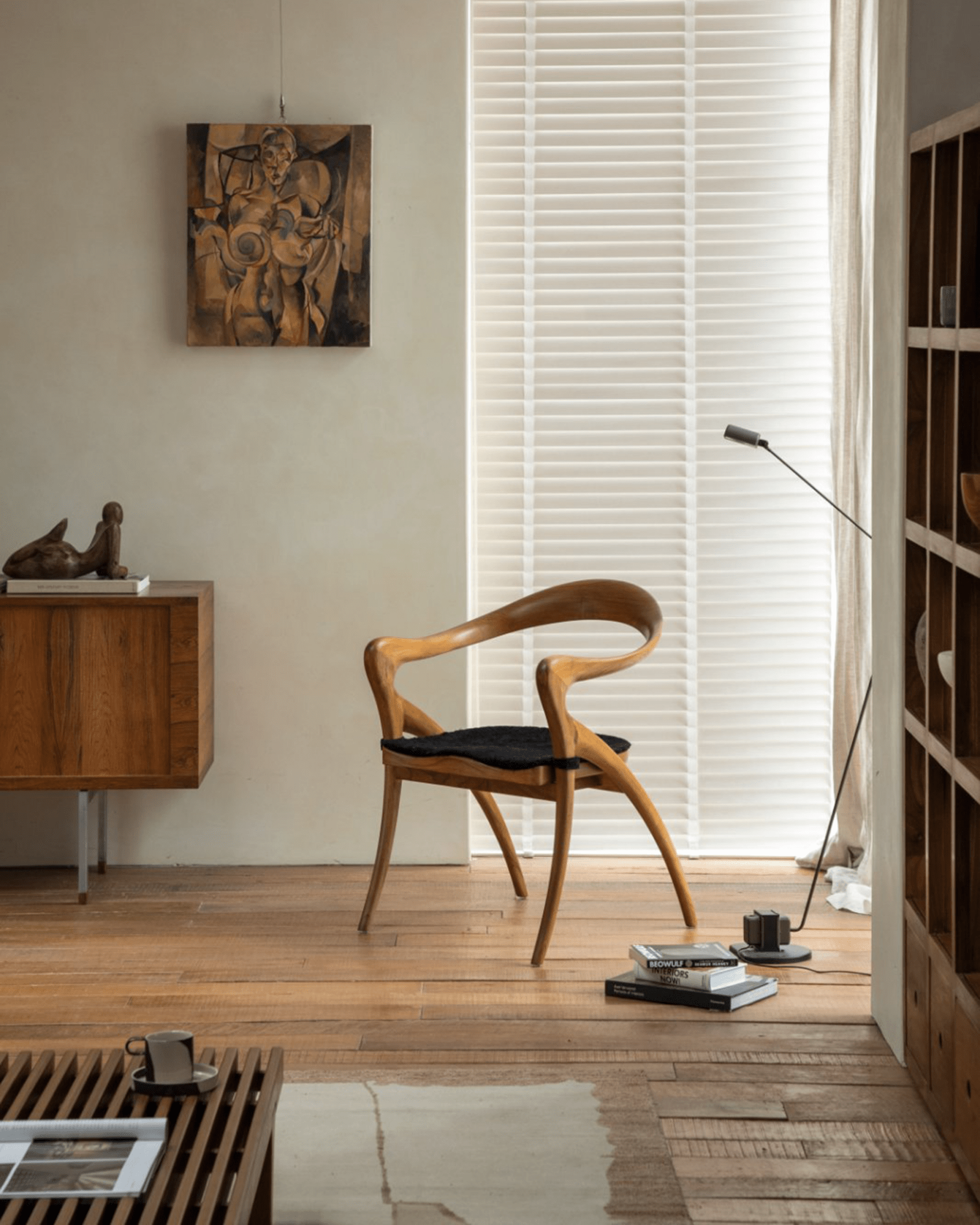 Olivia Chair in modern interior with solid teak wood, curved back and black seat cushion. Modern design