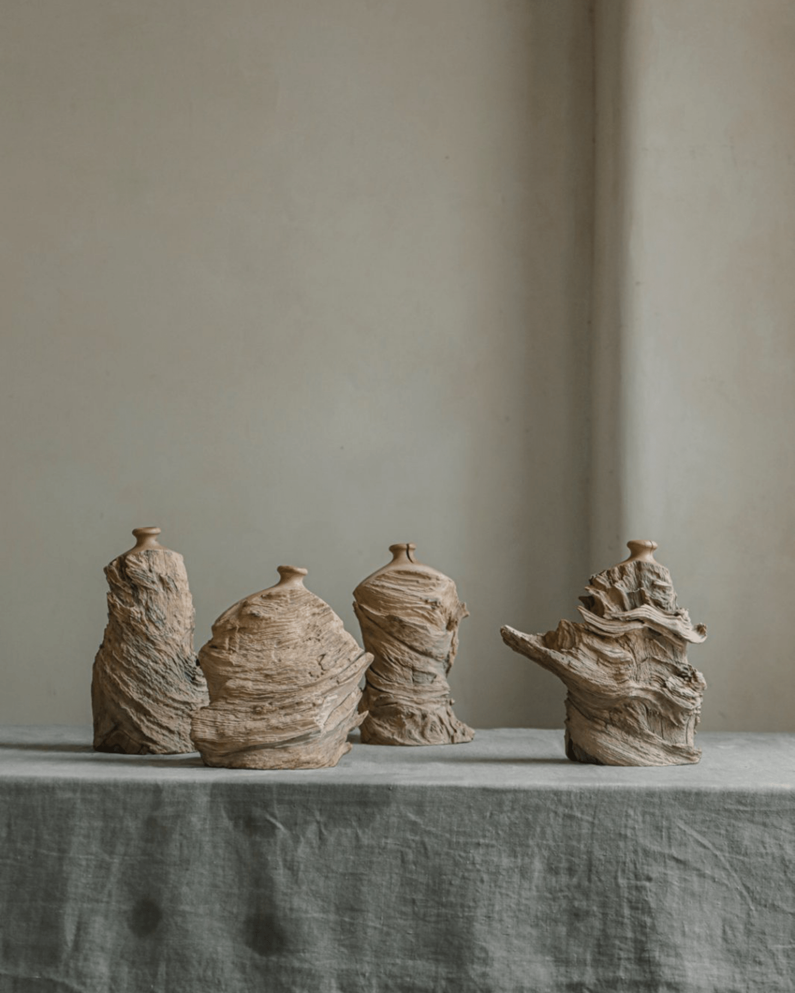 Set of four unique wooden wavy vases on a gray table. Handcrafted vases in various sizes and shapes.